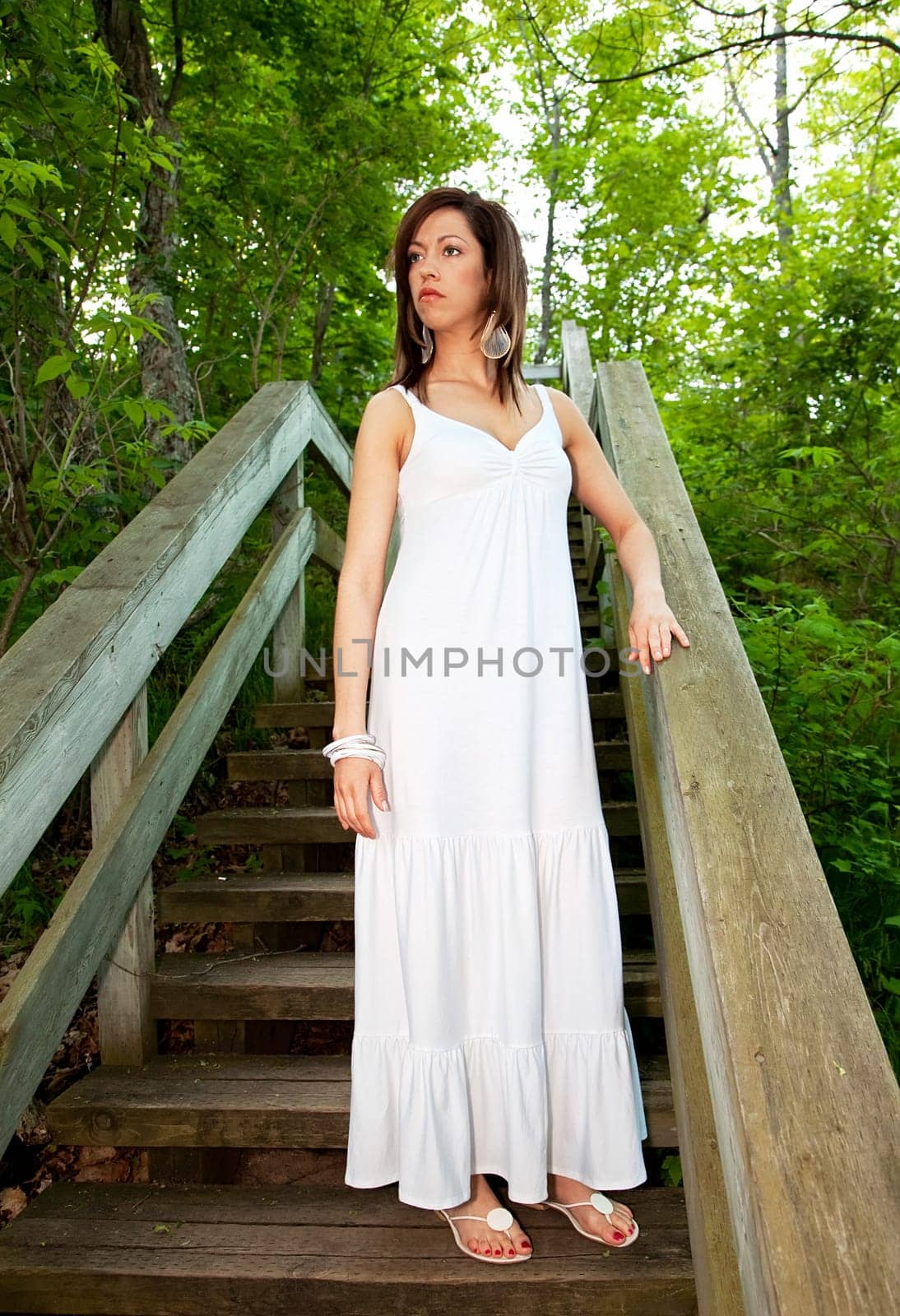 A beautiful woman standing on wooden steps in the forest.