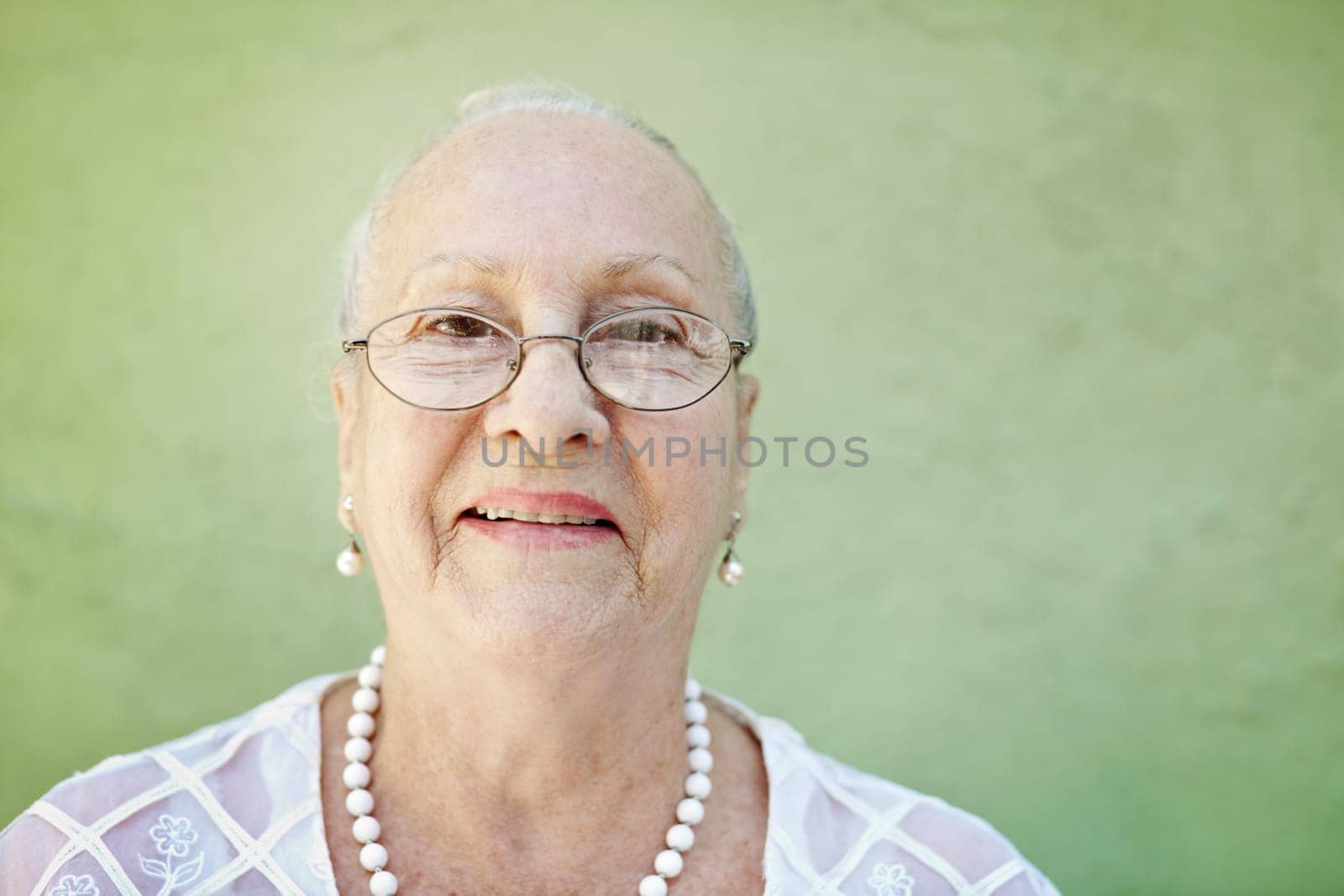 portrait of senior caucasian woman looking at camera against green wall and smiling. Horizontal shape, copy space