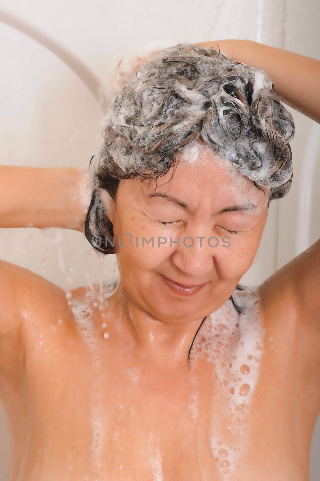 Asian woman showering and washing her hair with shampoo