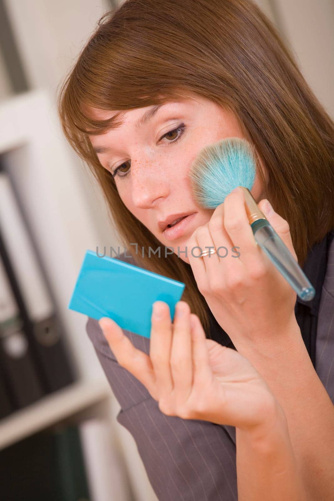 young woman applying make up by office work