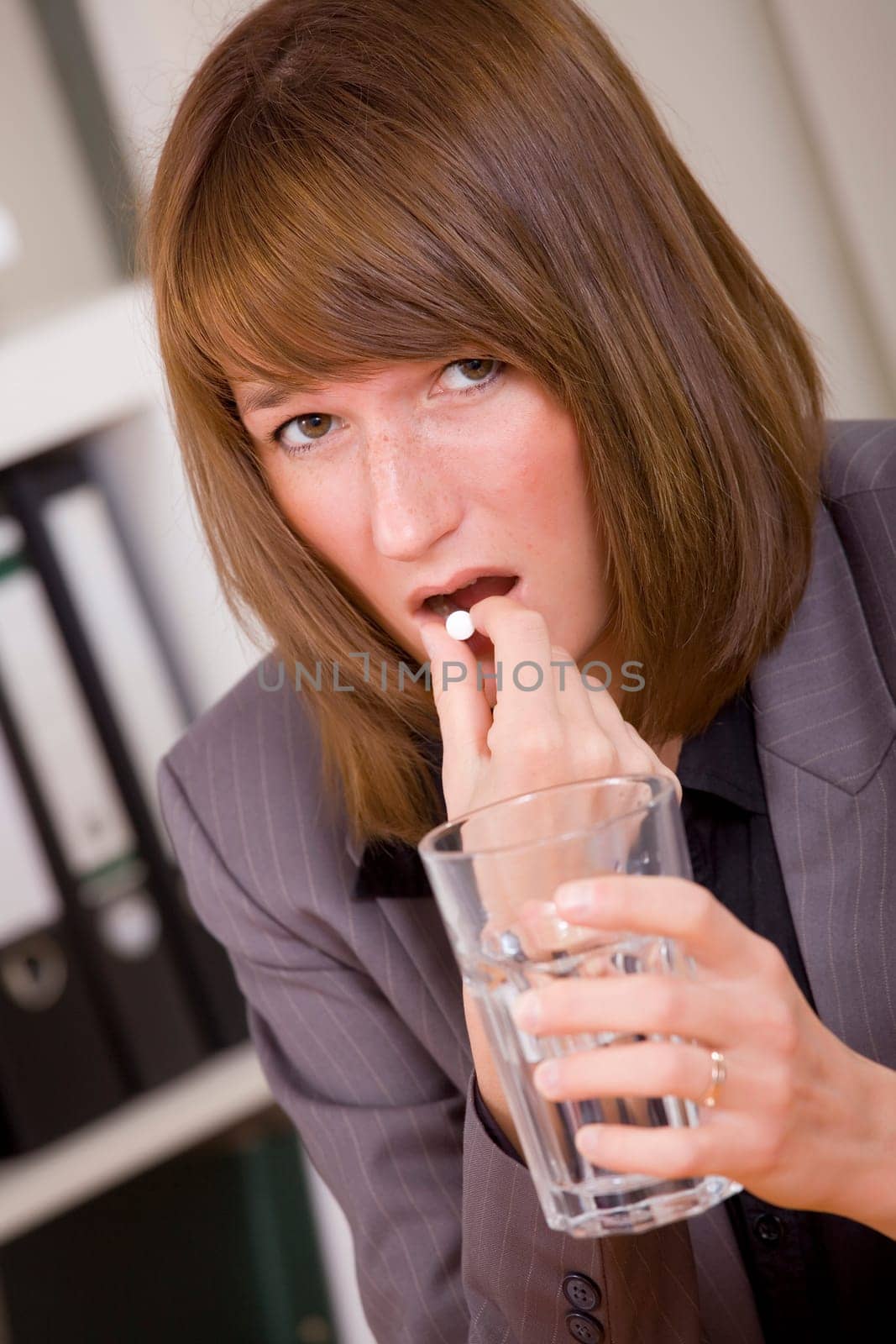 stressed business woman taking pills by office work