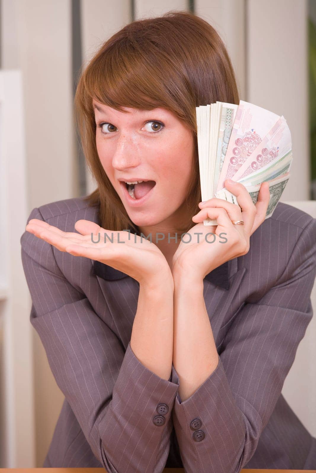 happy business woman with stack of money in office