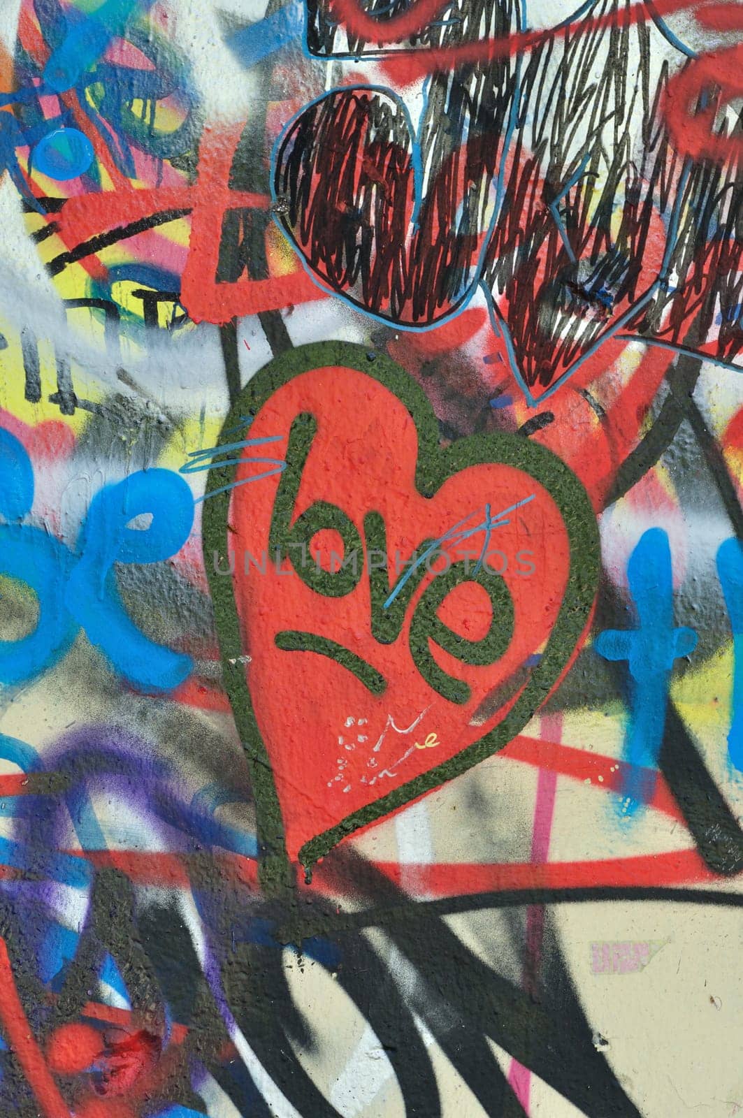 Dirty love graffiti over messy tagged urban wall background. Heart of the city.