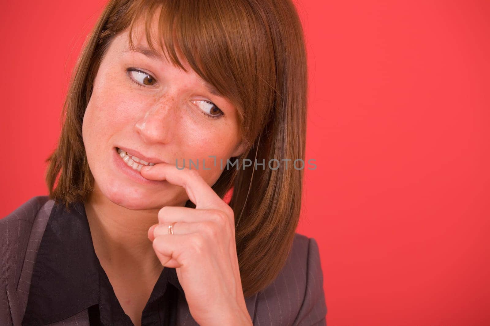 nervous businesswoman biting her nails on red background