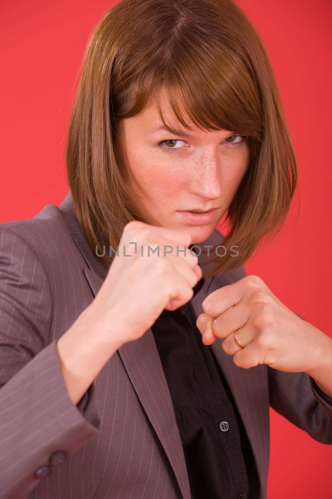 business woman in fighting stance on red background
