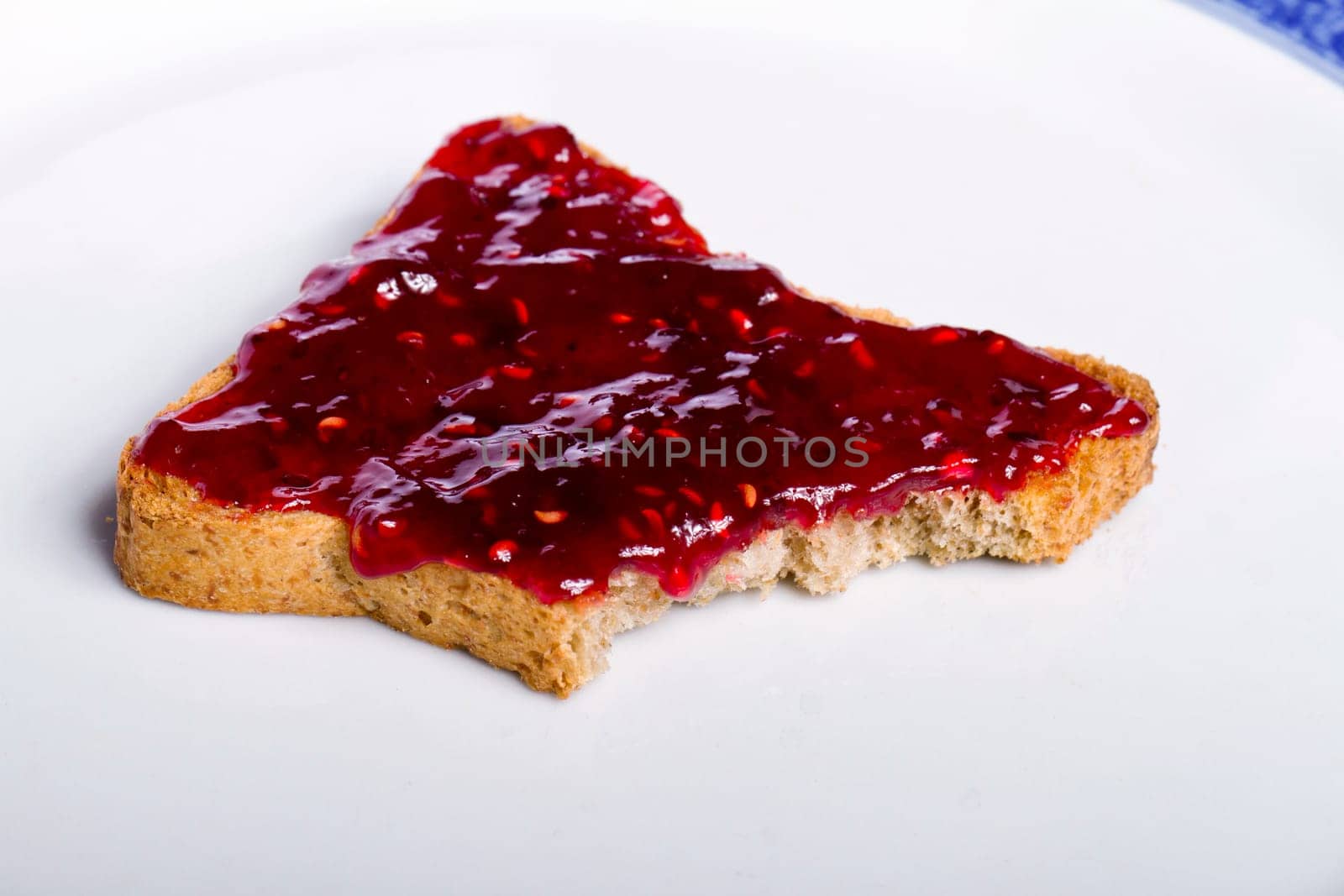 Close view of a toasted bread with berry jam spread  isolated on a white background.