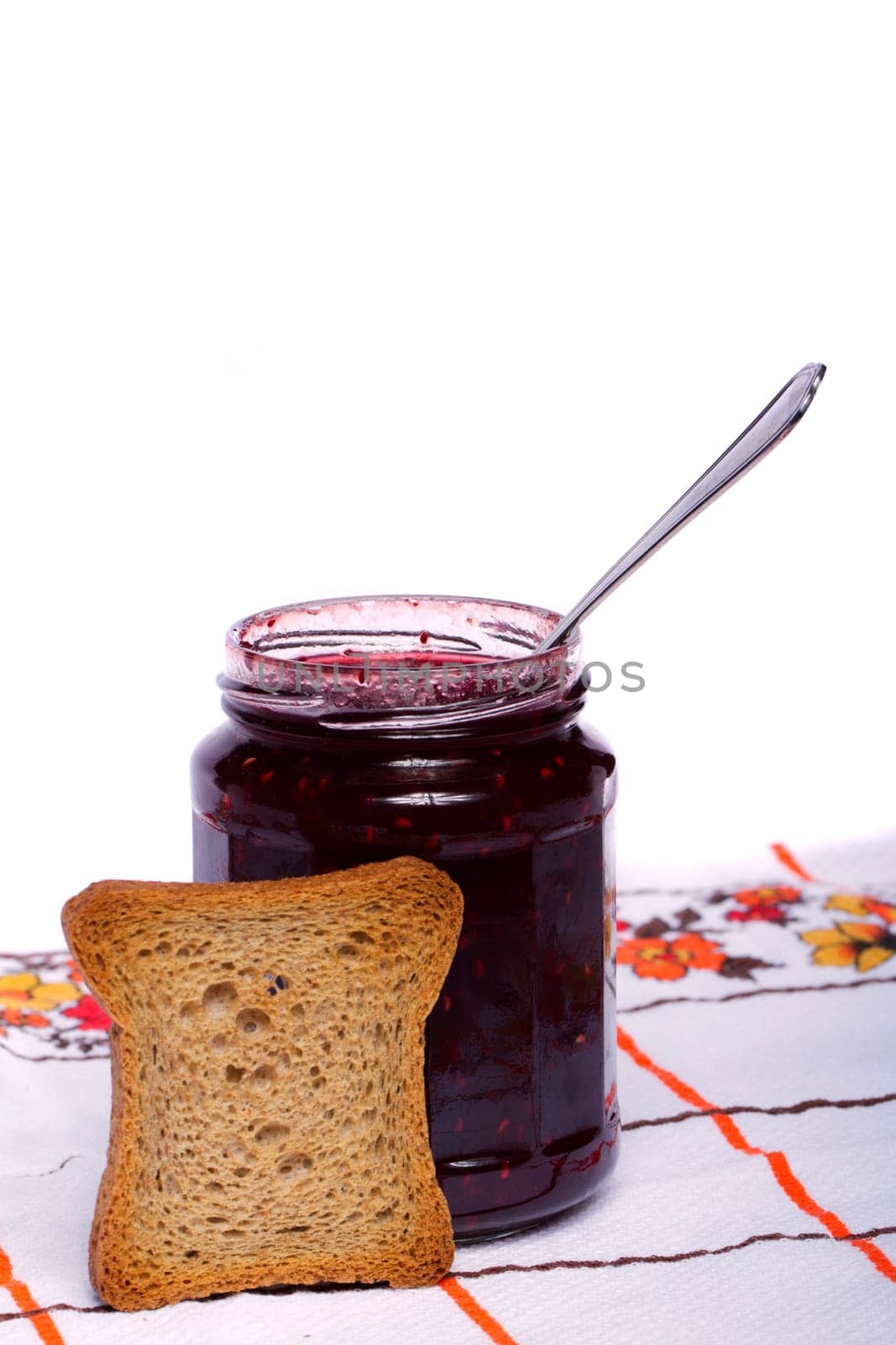 Close view of a toasted bread with berry jam jar isolated on a white background.