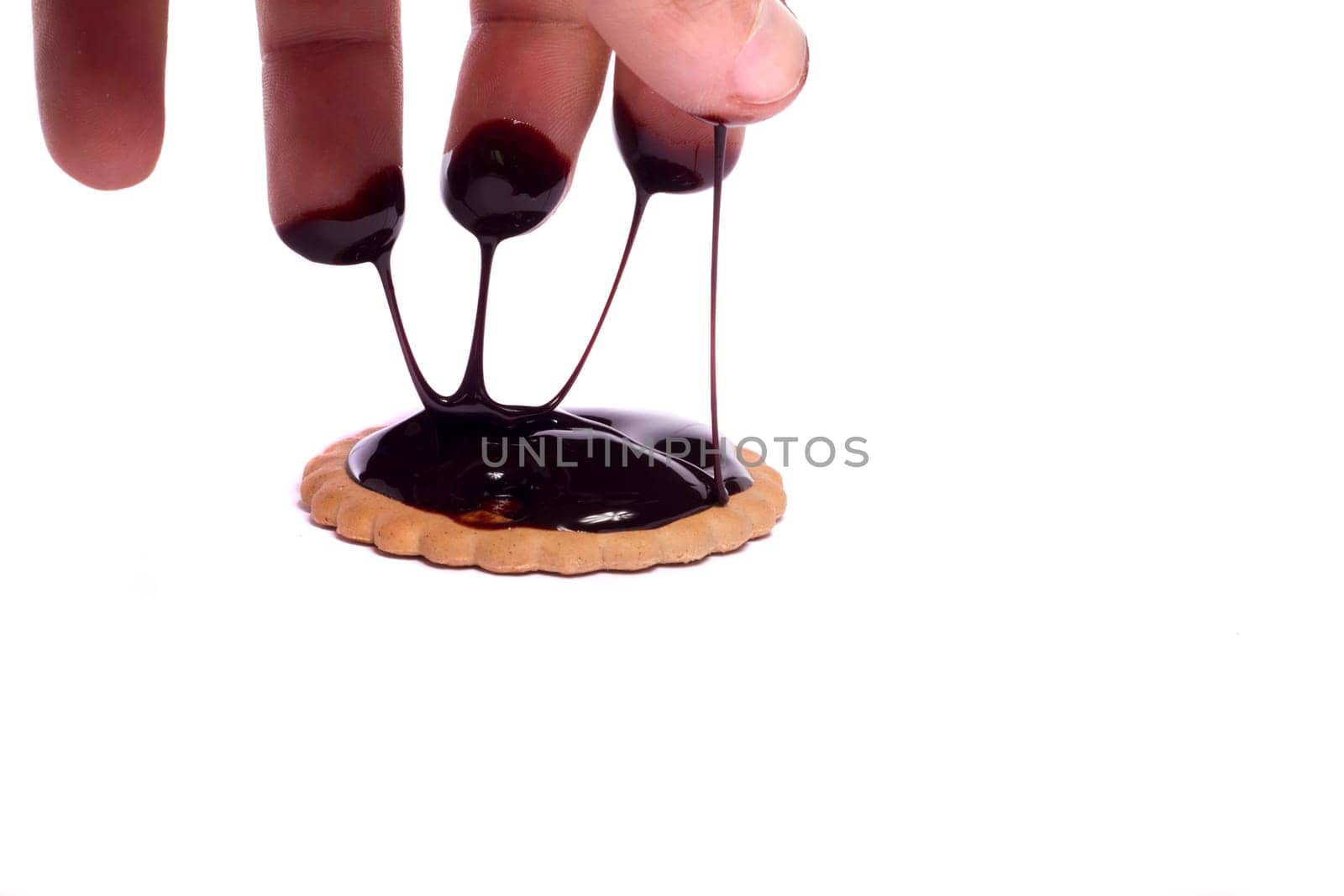 View of a round biscuit isolated on a white background with a drip of dark chocolate.