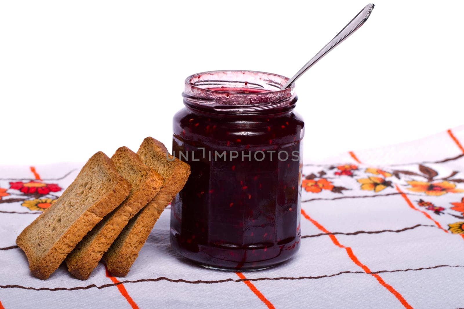 Close view of a toasted bread with berry jam jar isolated on a white background.
