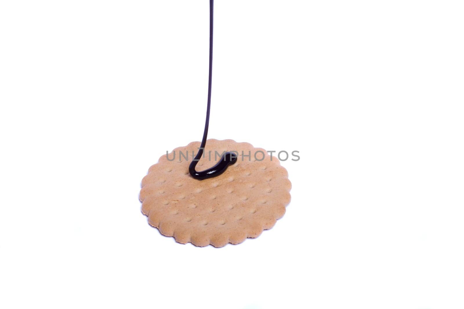 View of a round biscuit isolated on a white background with a drip of dark chocolate.