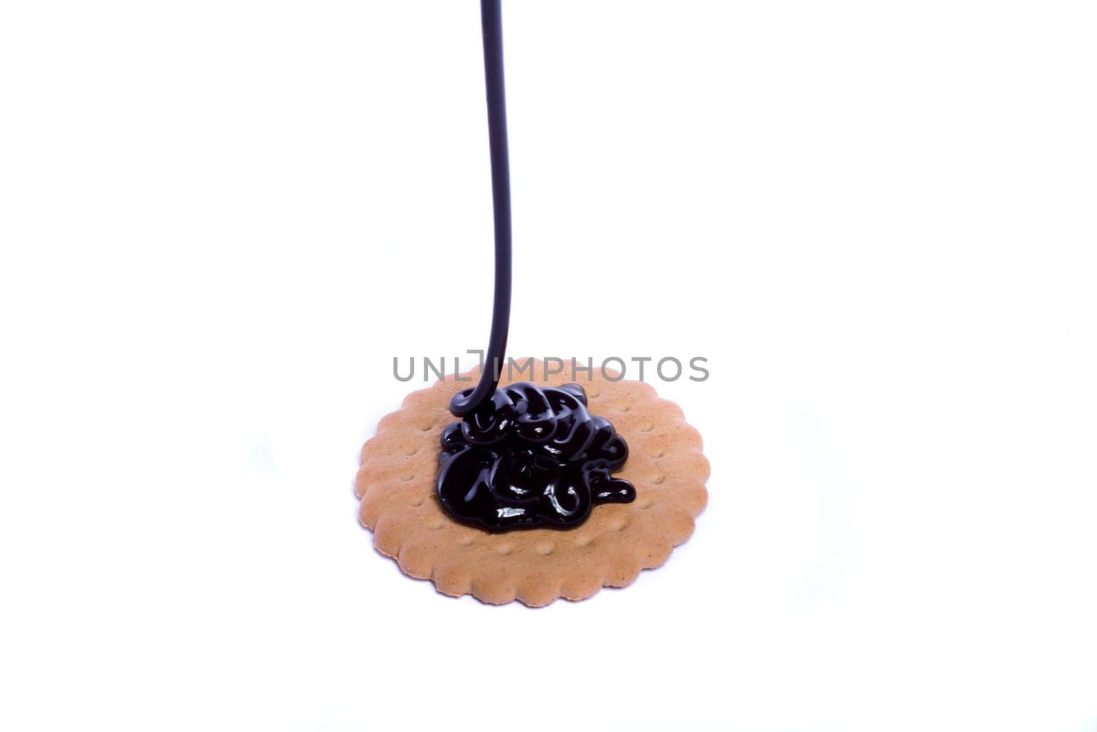View of a round biscuit isolated on a white background with a drip of dark chocolate.