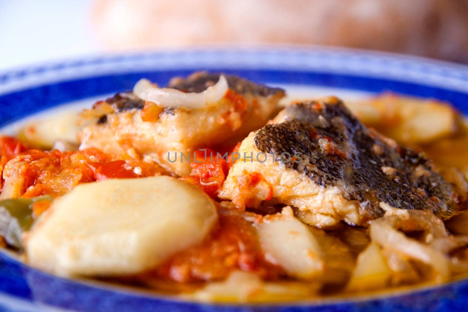 Close up view of a Portuguese meal of cod fish, potatoes and tomato.