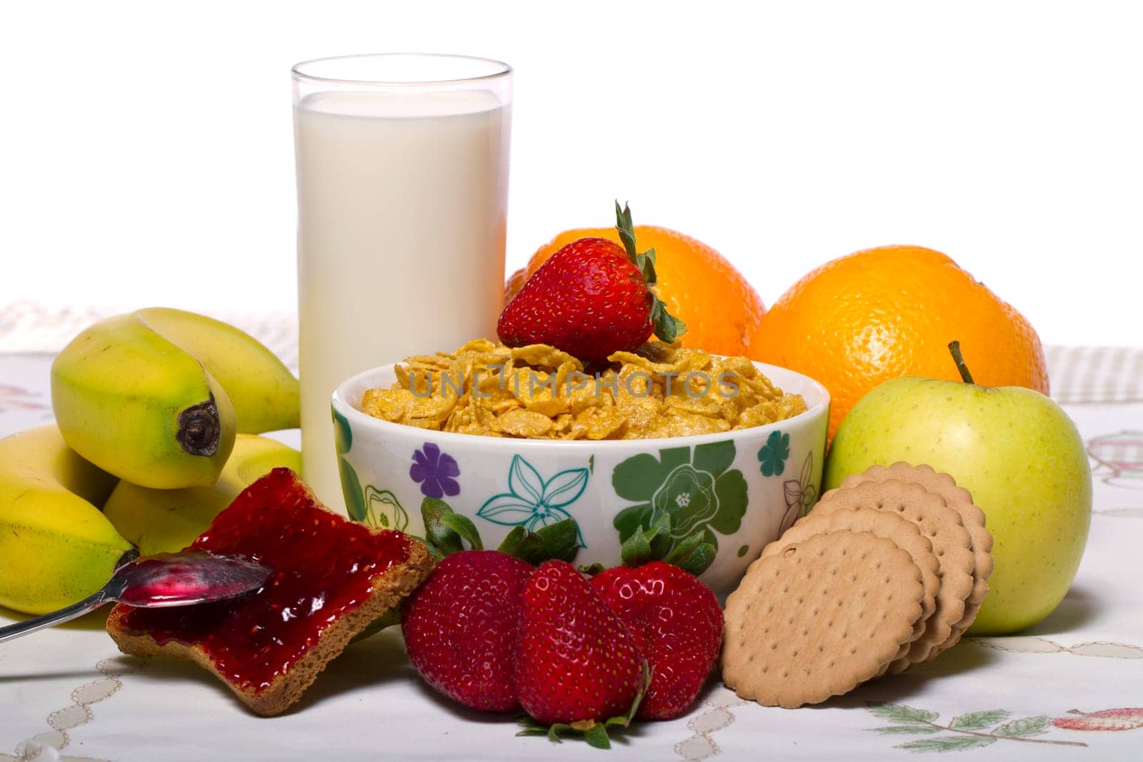 View of a bowl of cereals surrounded by fruit and milk.