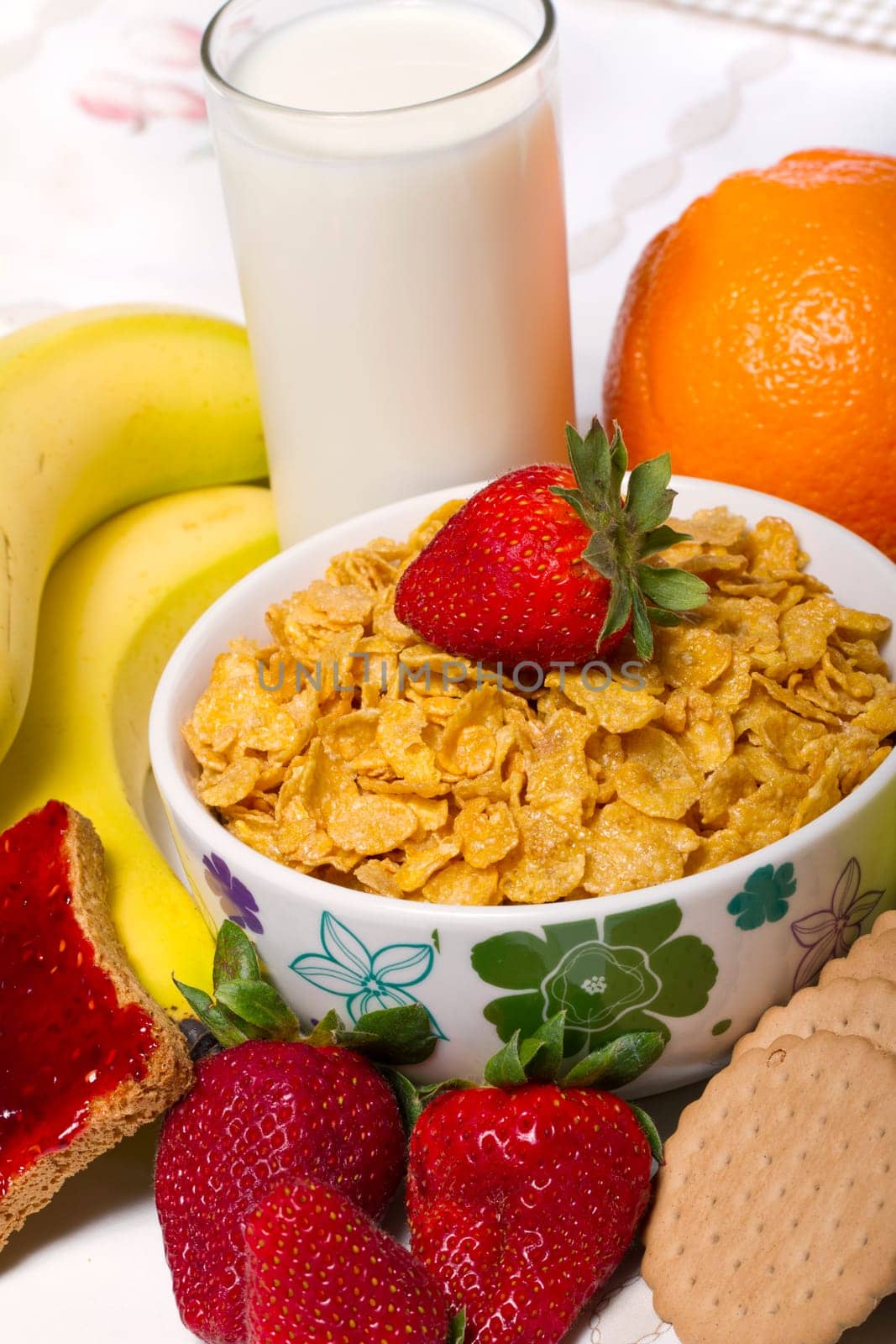View of a bowl of cereals surrounded by fruit and milk.