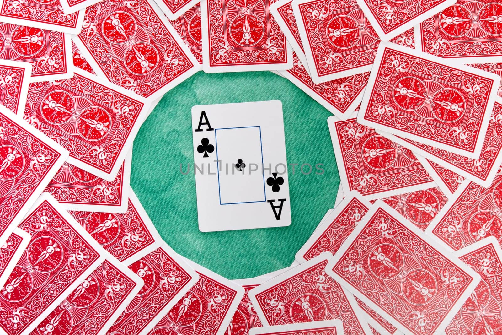 Close up view of a bunch of flipped playing cards spread on a green cloth table.