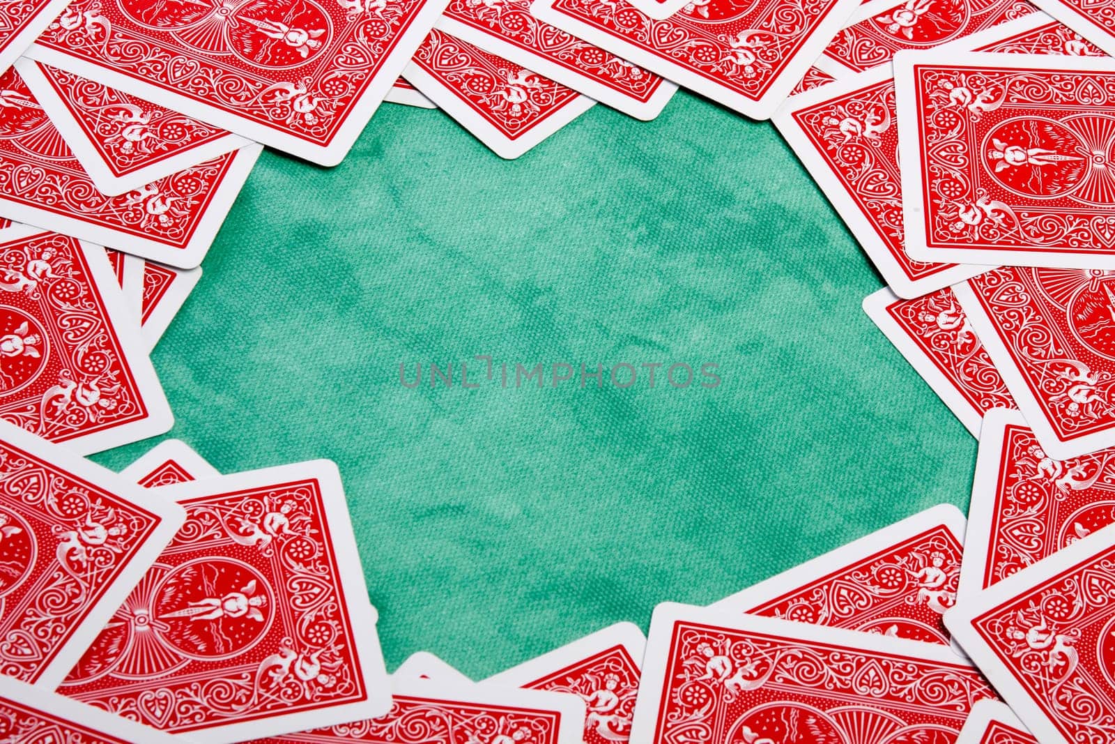 Close up view of a bunch of flipped playing cards spread on a green cloth table.