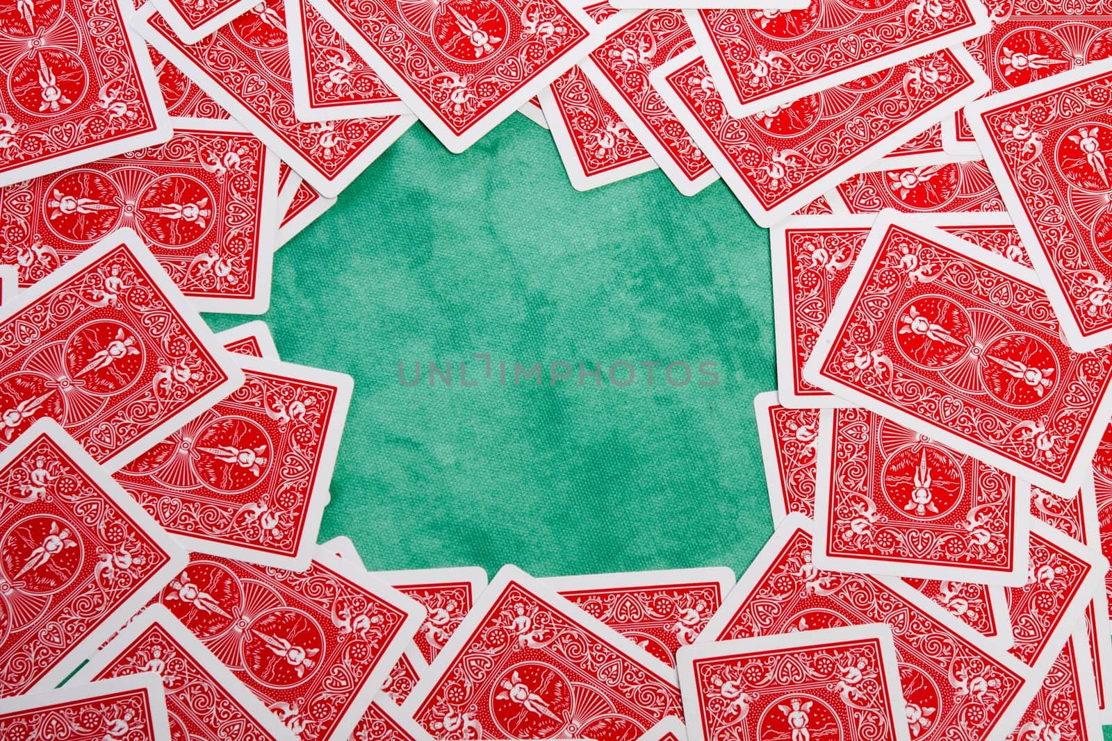 Close up view of a bunch of flipped playing cards spread on a green cloth table.