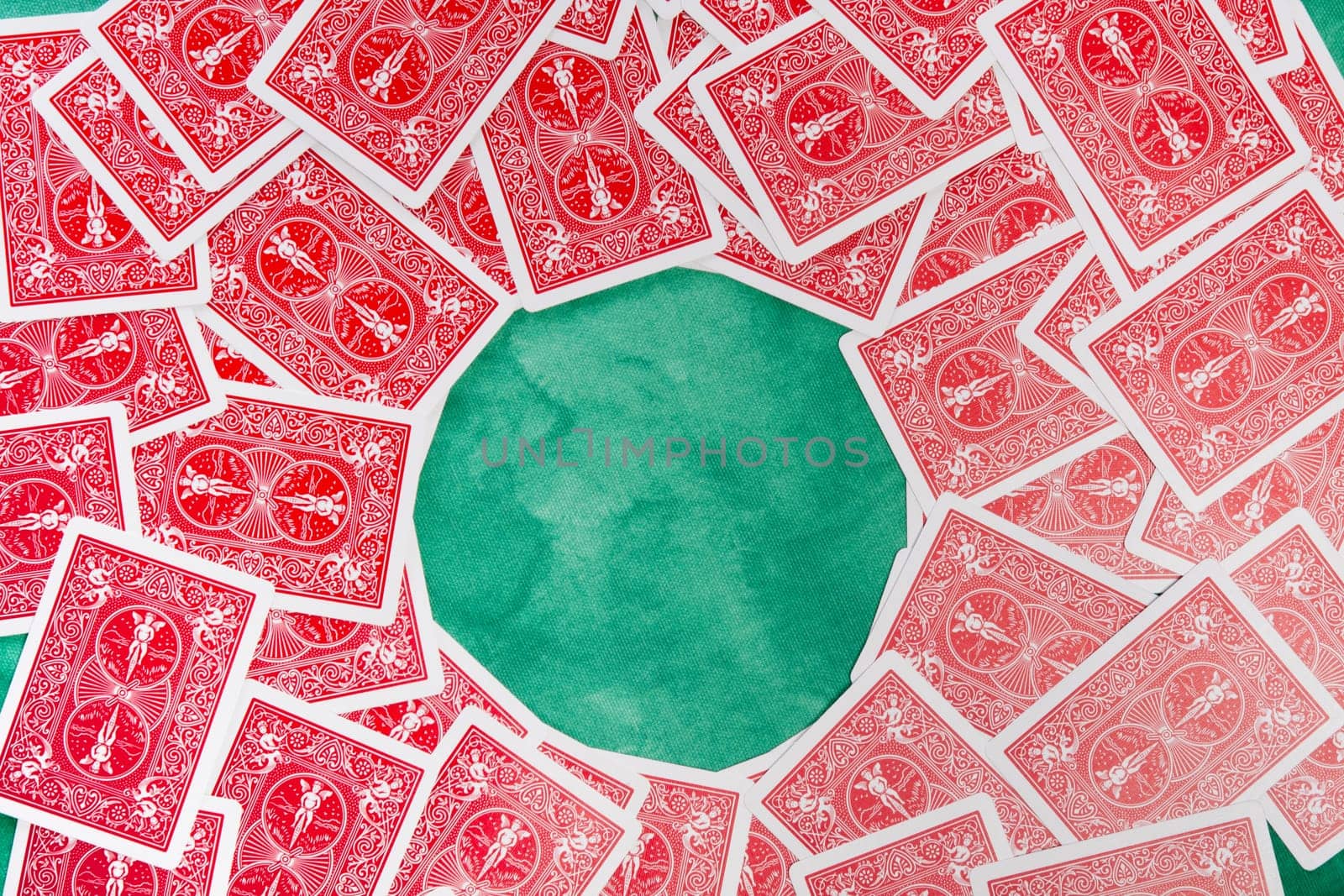Close up view of a bunch of flipped playing cards spread on a green cloth table.