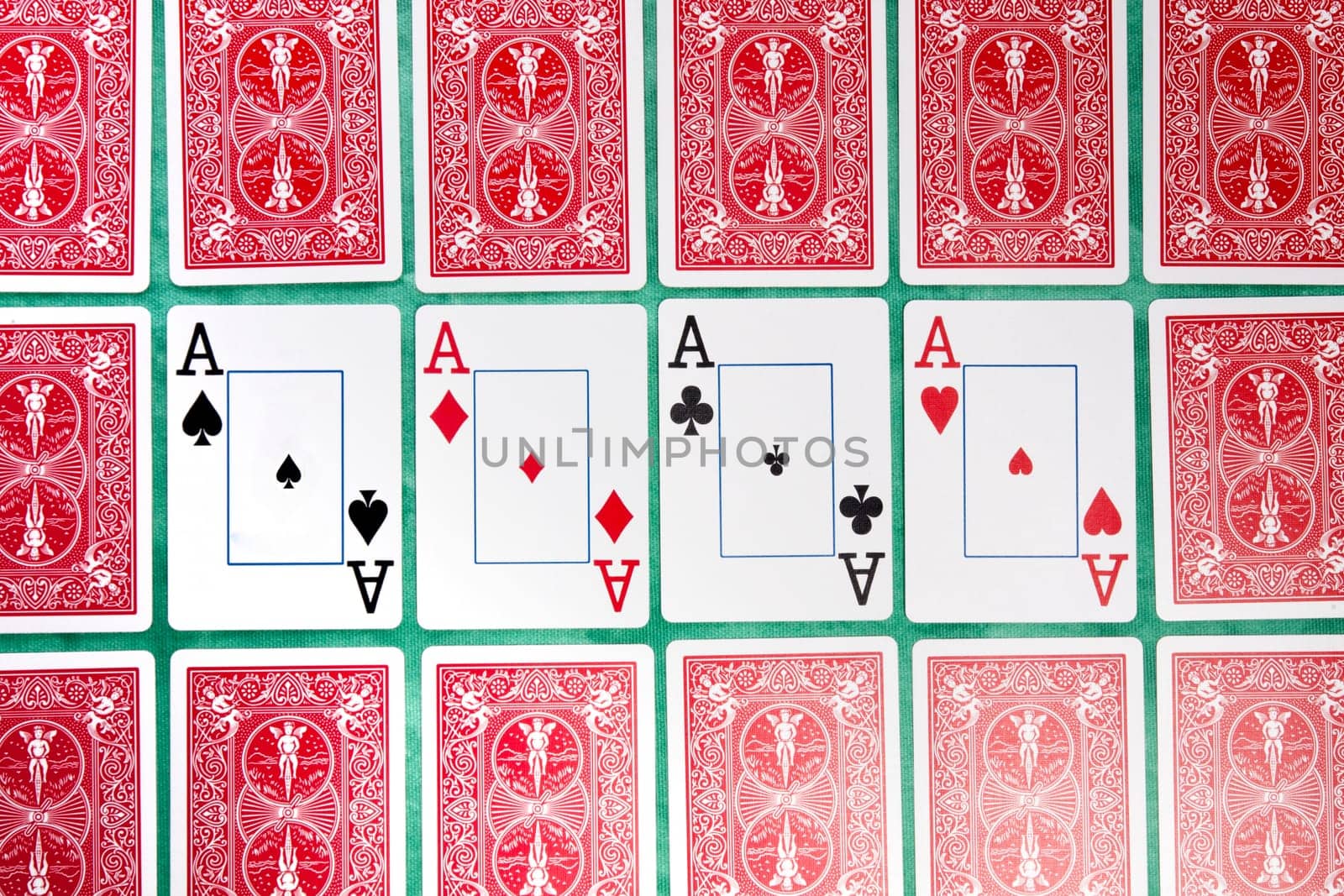 Close up view of a bunch of flipped playing cards spread on a green cloth table.
