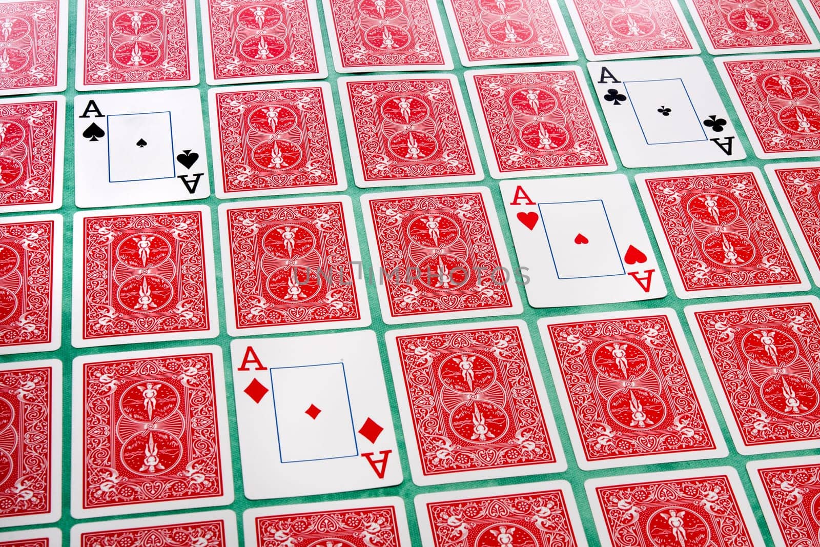Close up view of a bunch of flipped playing cards spread on a green cloth table.