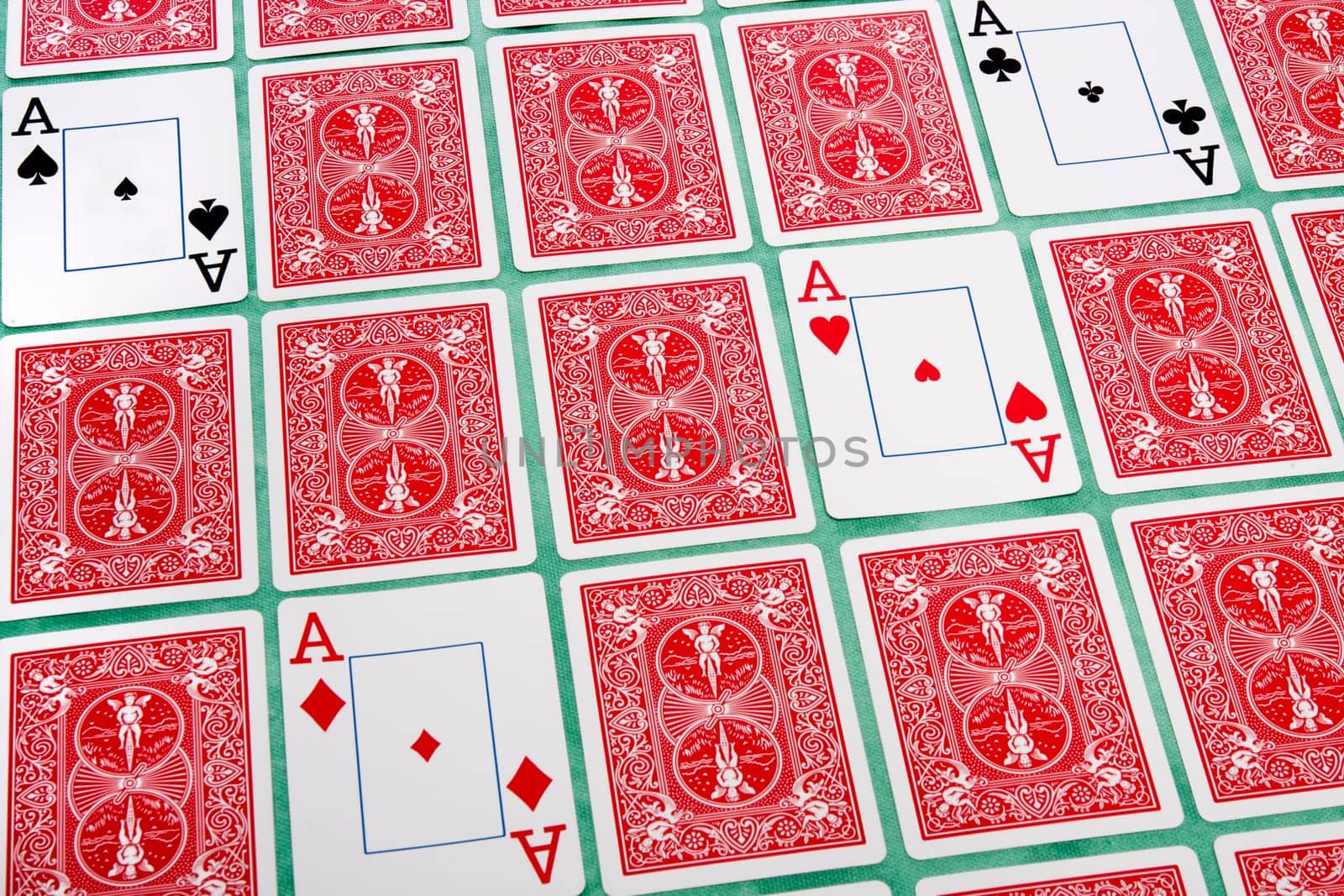 Close up view of a bunch of flipped playing cards spread on a green cloth table.