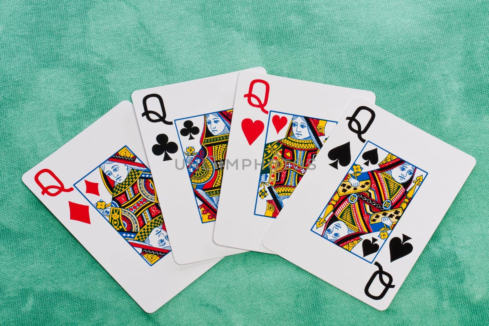 Close up view of a set of four queens spread on a green cloth table.