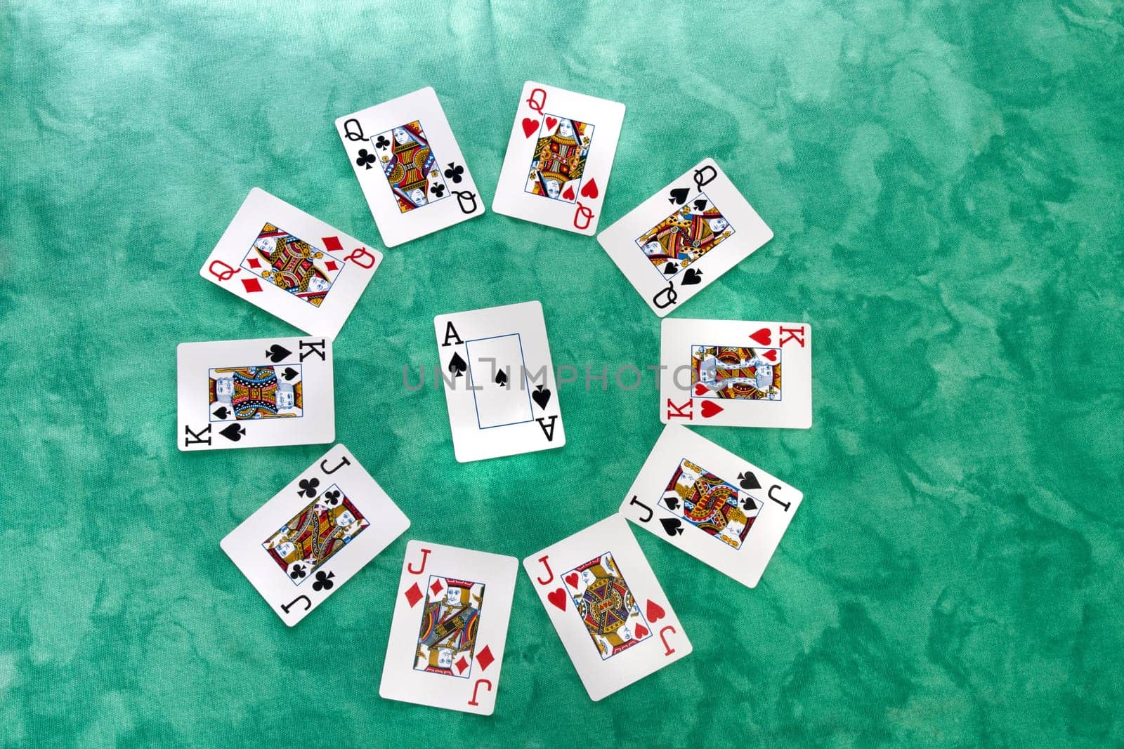 Close up view of a circle of playing cards spread on a green cloth table.