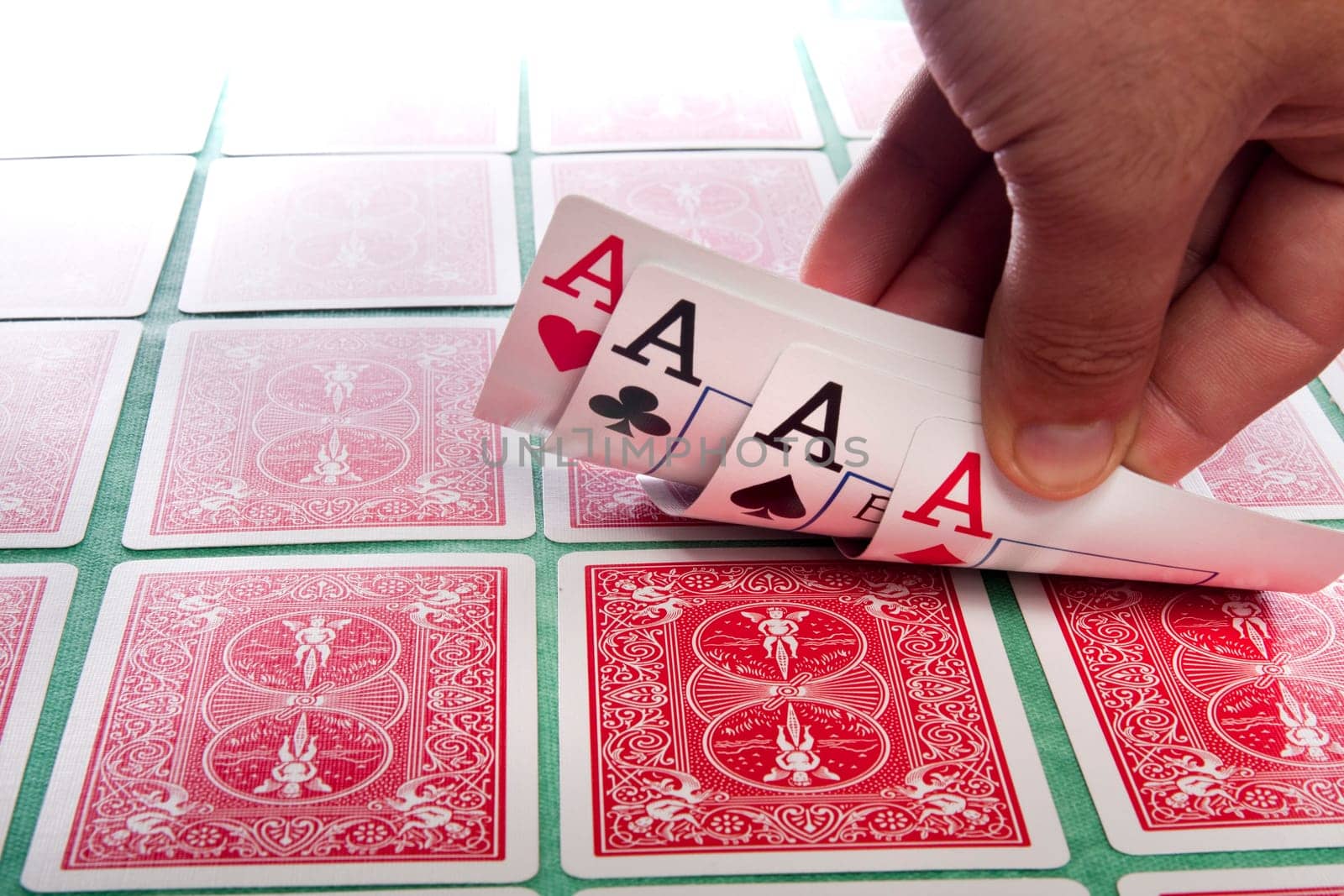Close up view of a bunch of flipped playing cards spread on a green cloth table.