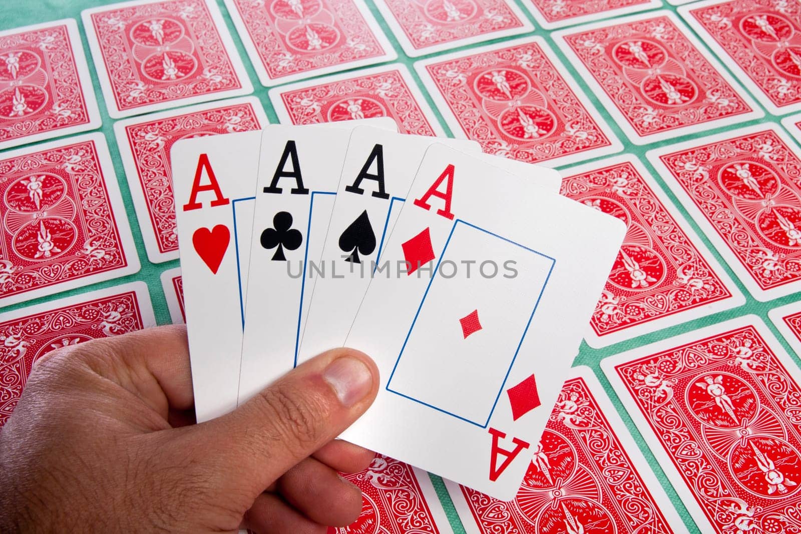 Close up view of a bunch of flipped playing cards spread on a green cloth table.