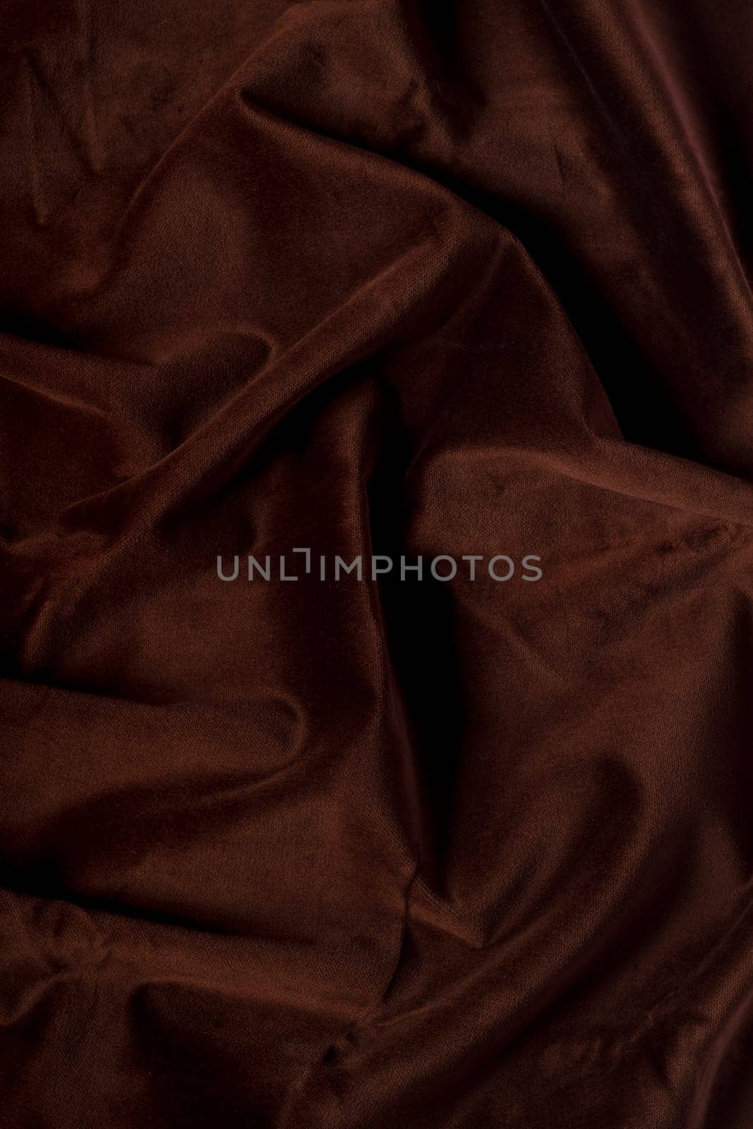 Close up view of a wrinkled dark brown silk fabric background.