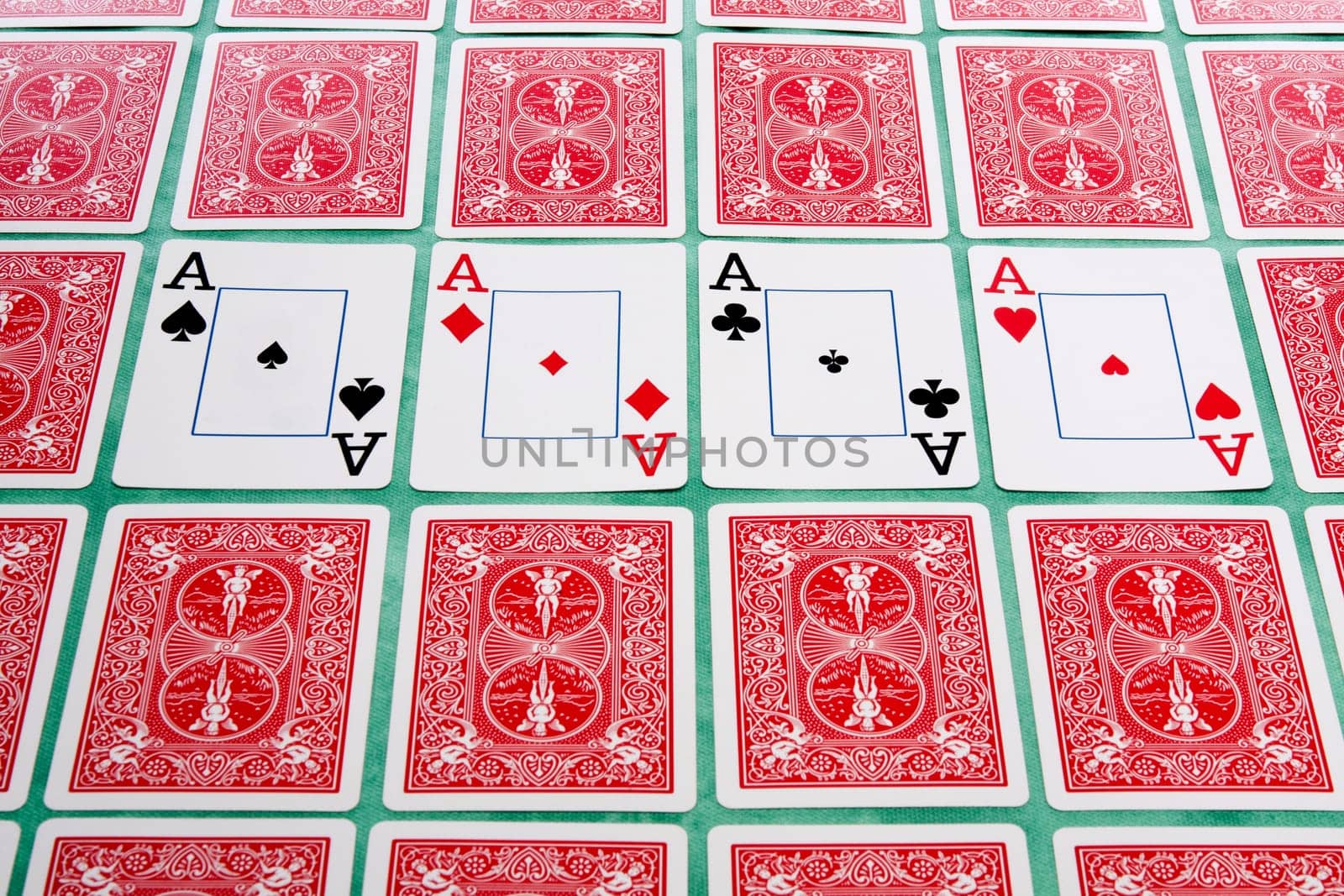 Close up view of a bunch of flipped playing cards spread on a green cloth table.