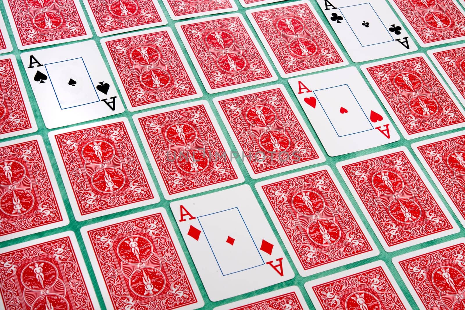 Close up view of a bunch of flipped playing cards spread on a green cloth table.