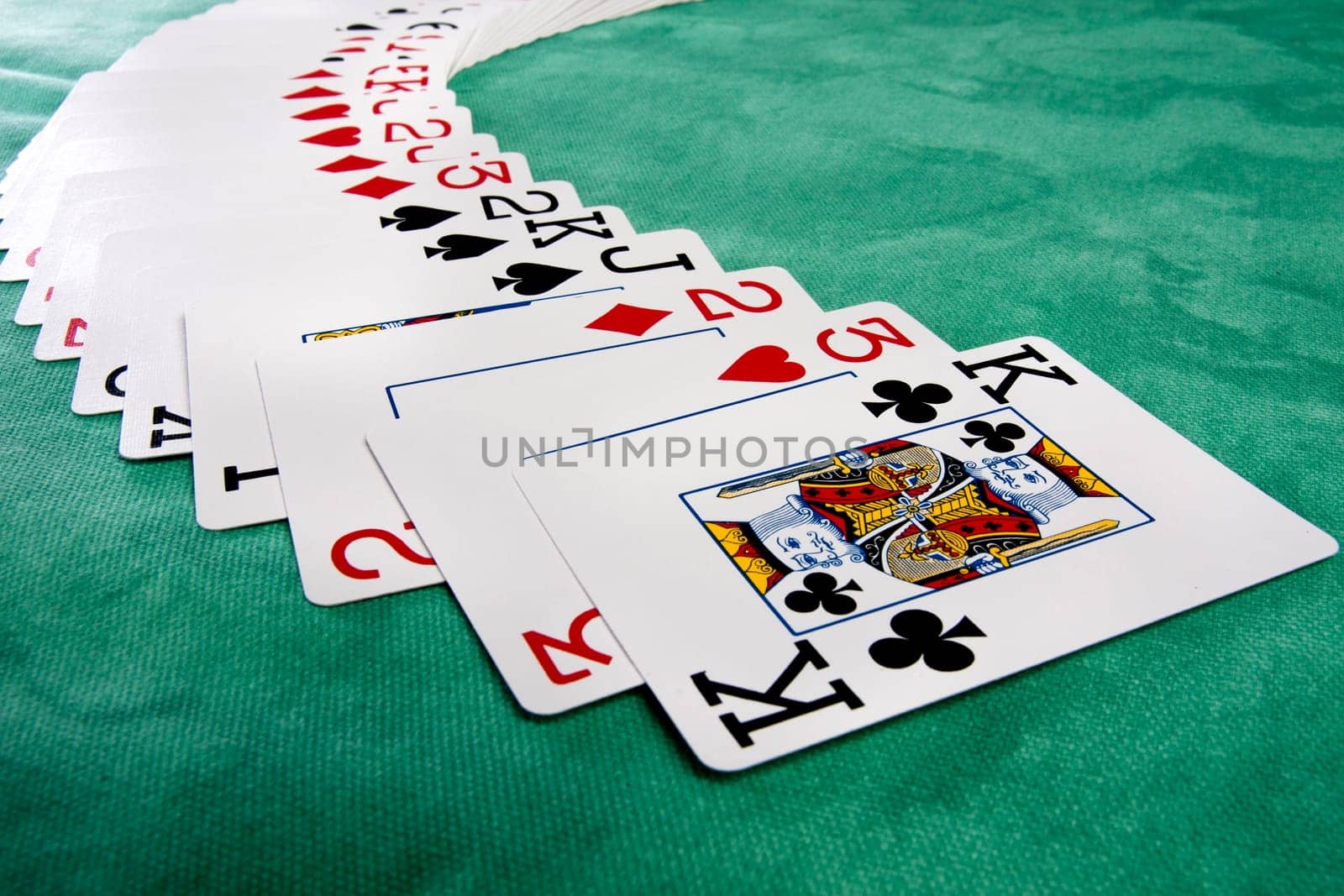 Close up view of a bunch cards spread on a green cloth table.