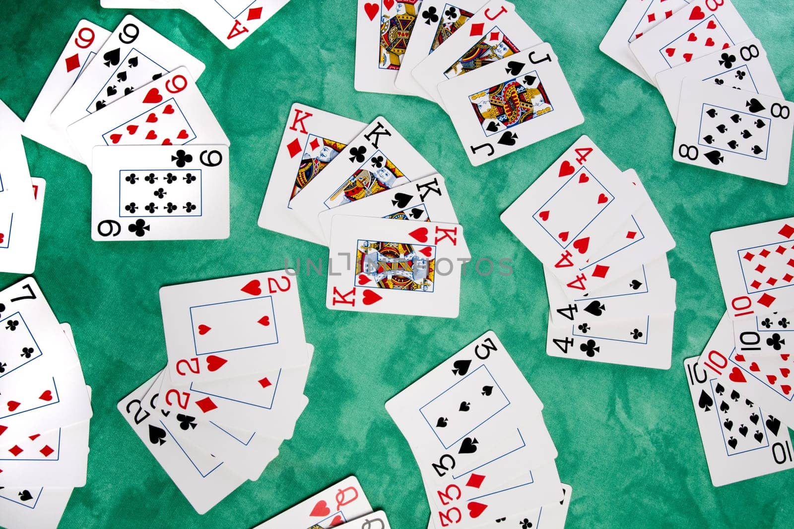Close up view of a bunch cards spread on a green cloth table.