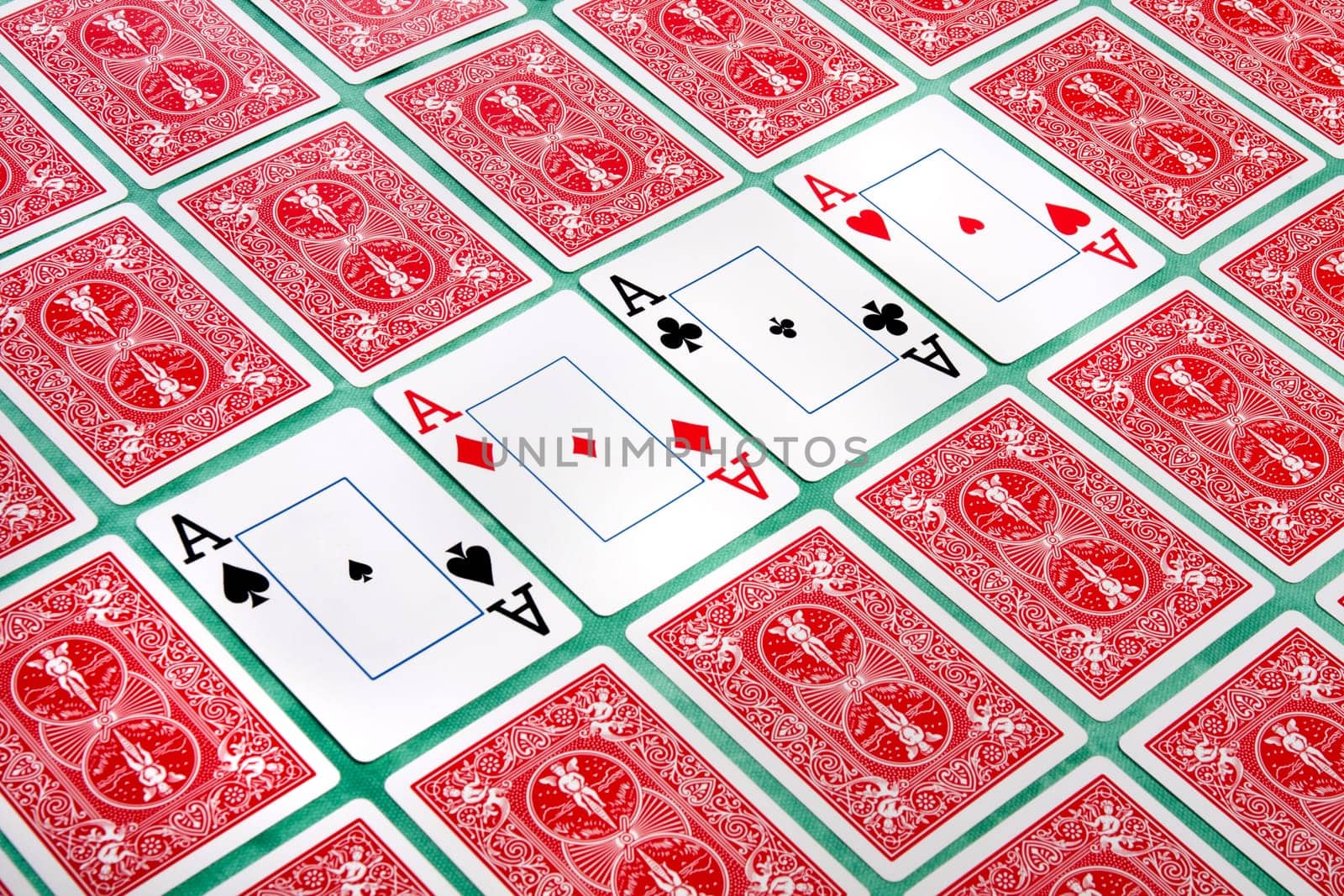 Close up view of a bunch of flipped playing cards spread on a green cloth table.