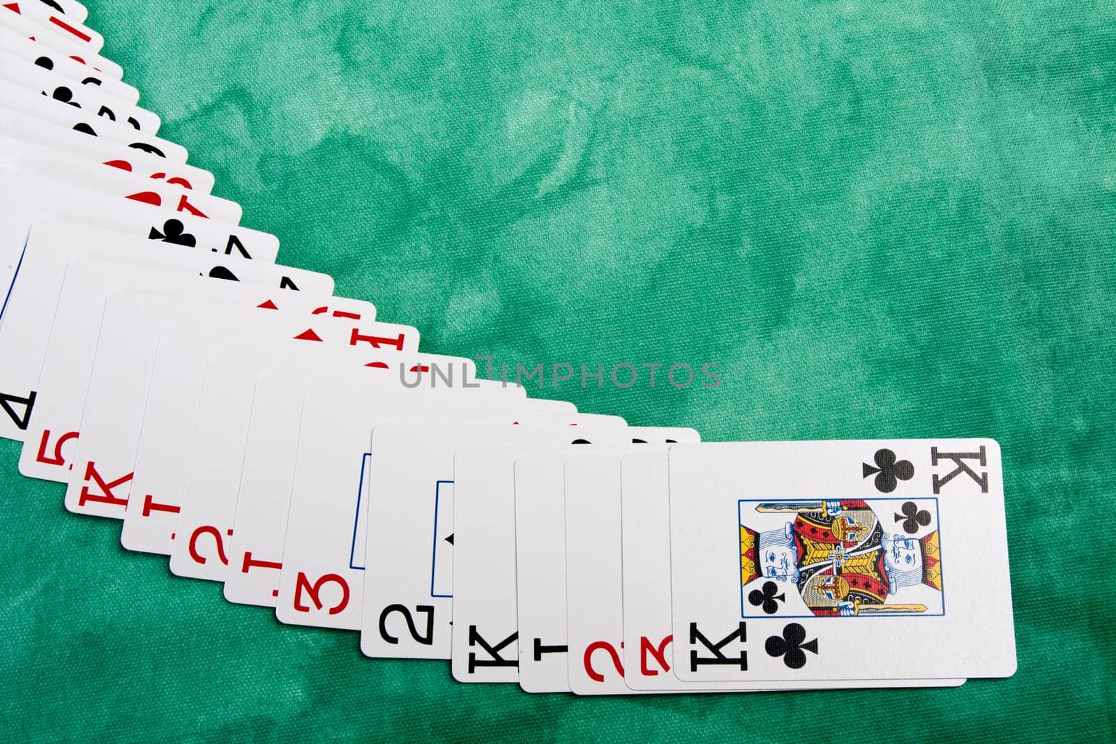 Close up view of a bunch cards spread on a green cloth table.