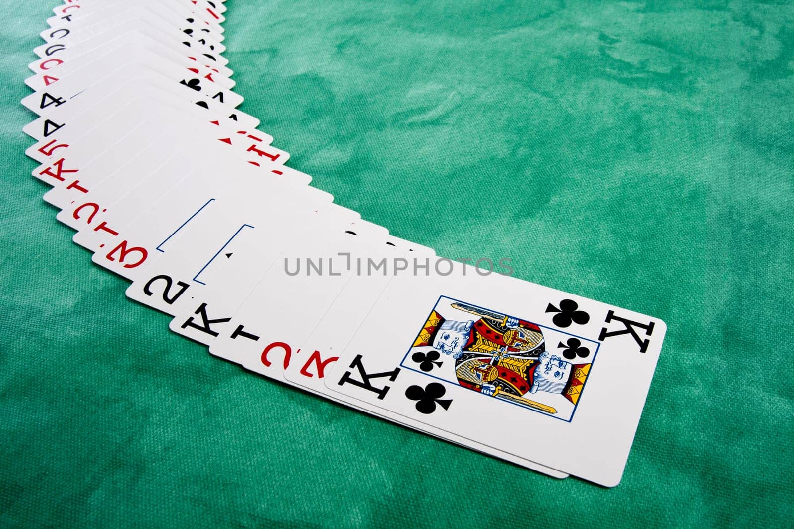 Close up view of a bunch cards spread on a green cloth table.
