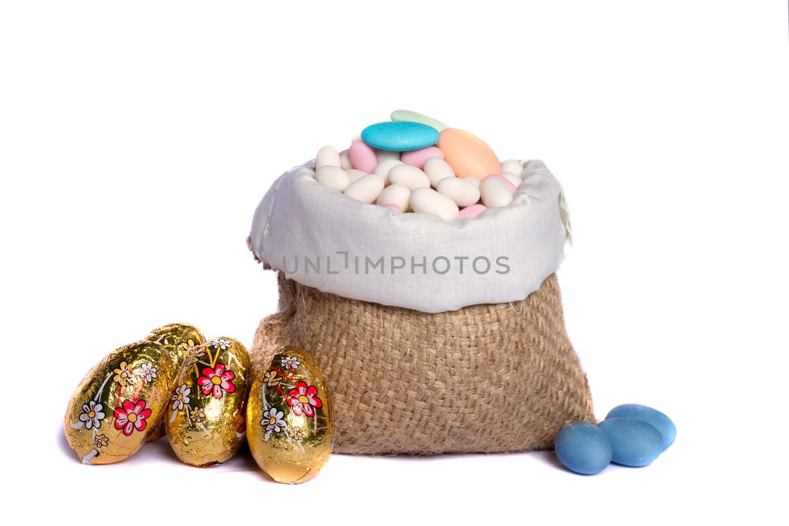 Close up view of sweet almonds and chocolate eggs inside a sack isolated on a white background.