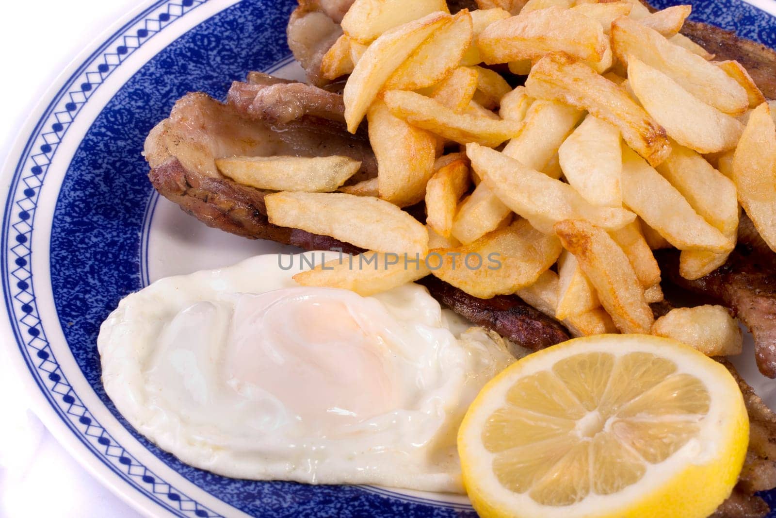 Close up view of a bunch of fried potatoes in slices, with egg and roasted meat.
