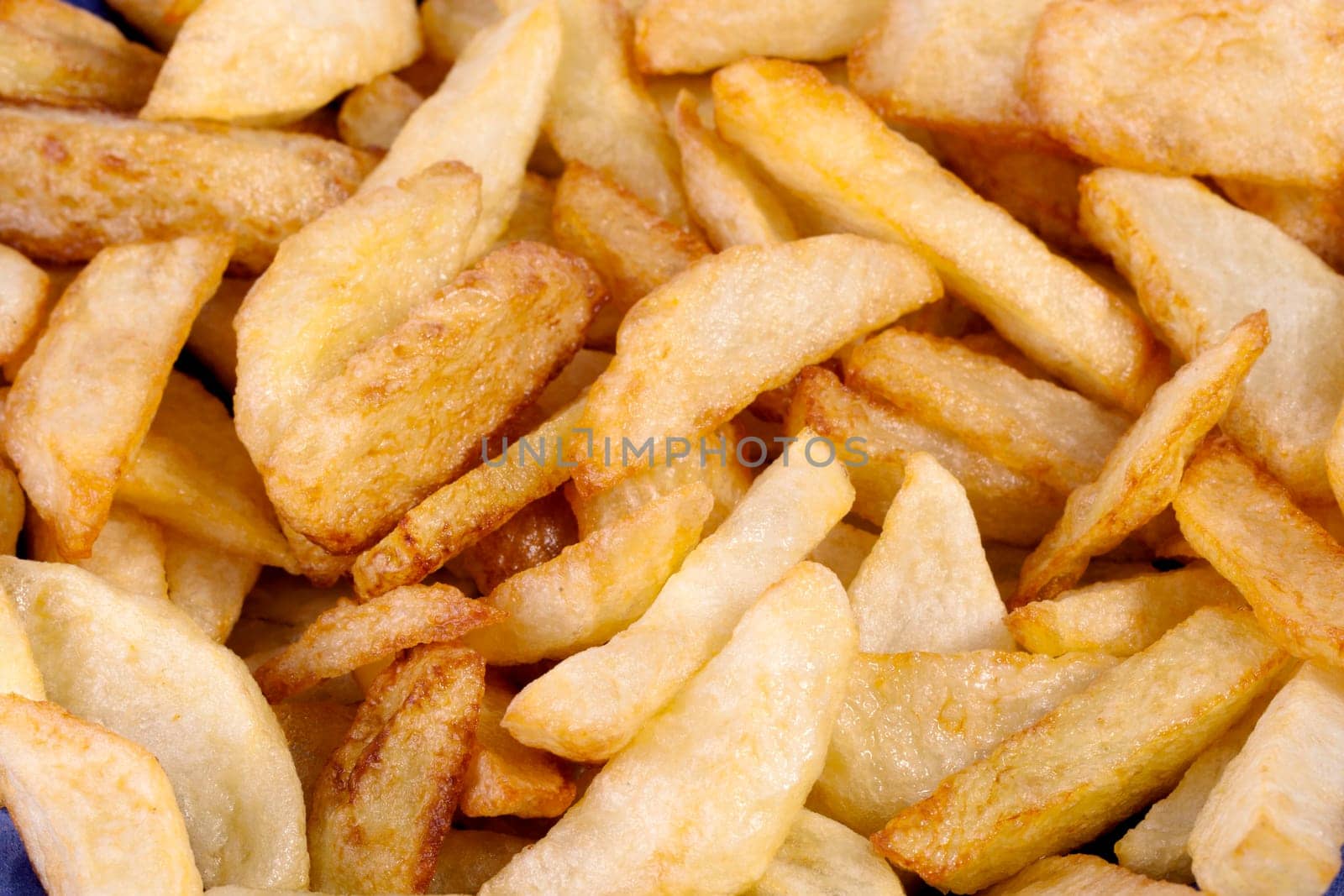 Close up view of a bunch of fried potatoes in slices.