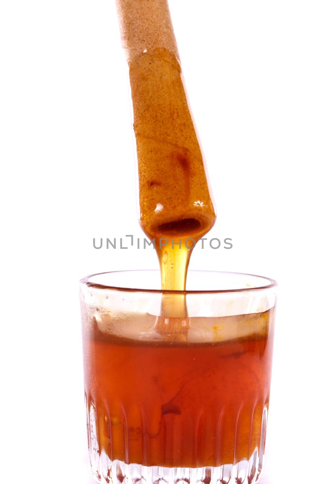 Close up view of a glass of honey and another of chocolate with cookie rolls.