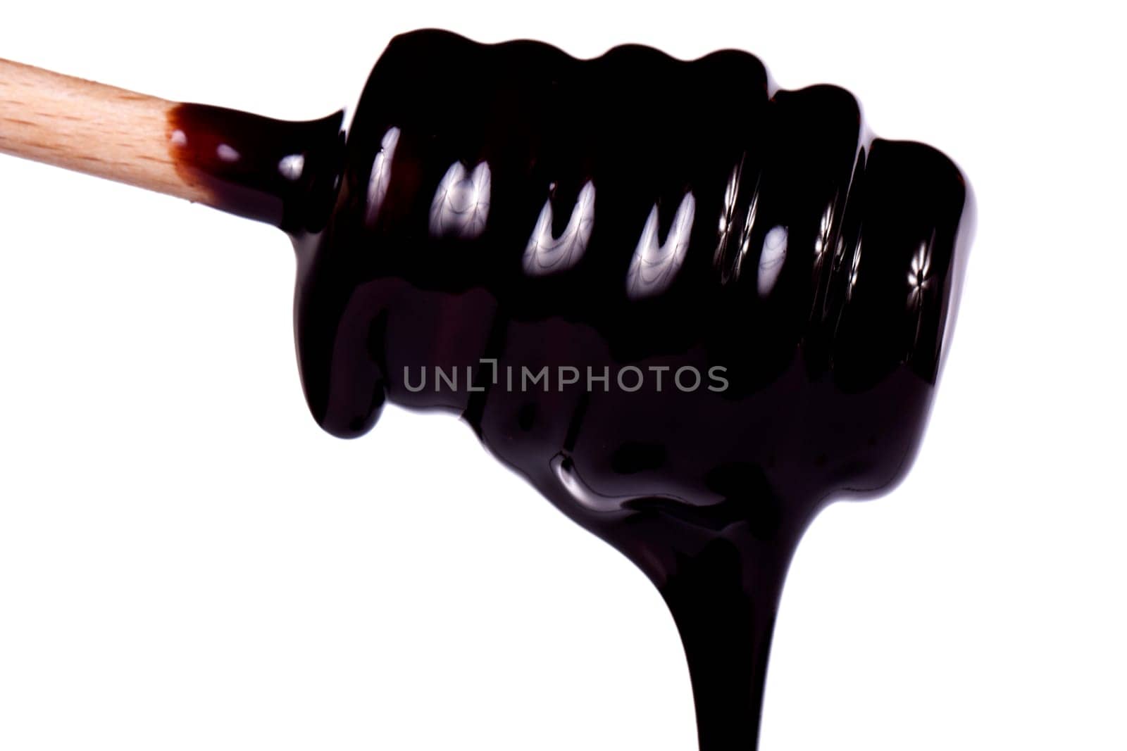 Close up view of a honey dipper with dark chocolate isolated on a white background.