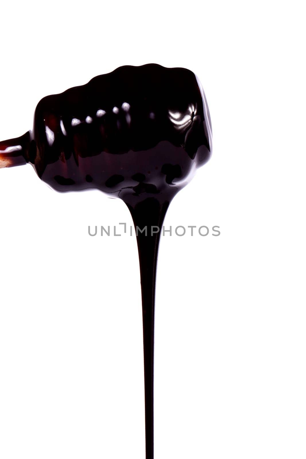 Close up view of a honey dipper with dark chocolate isolated on a white background.