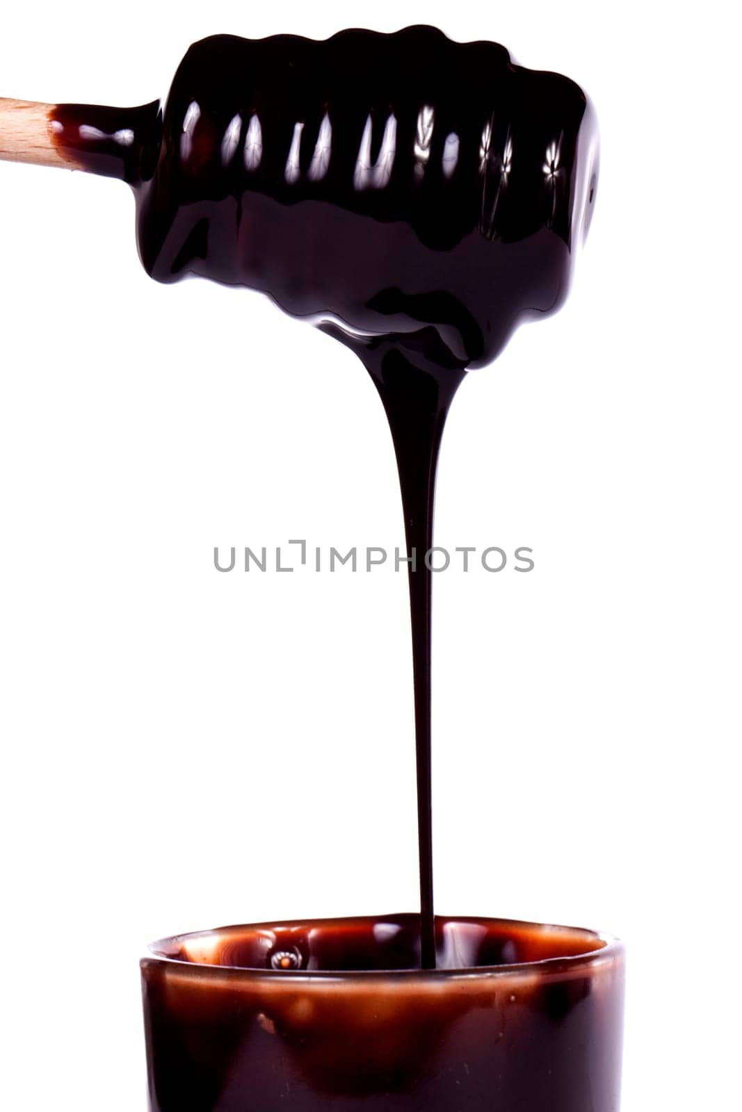Close up view of a honey dipper with dark chocolate isolated on a white background.