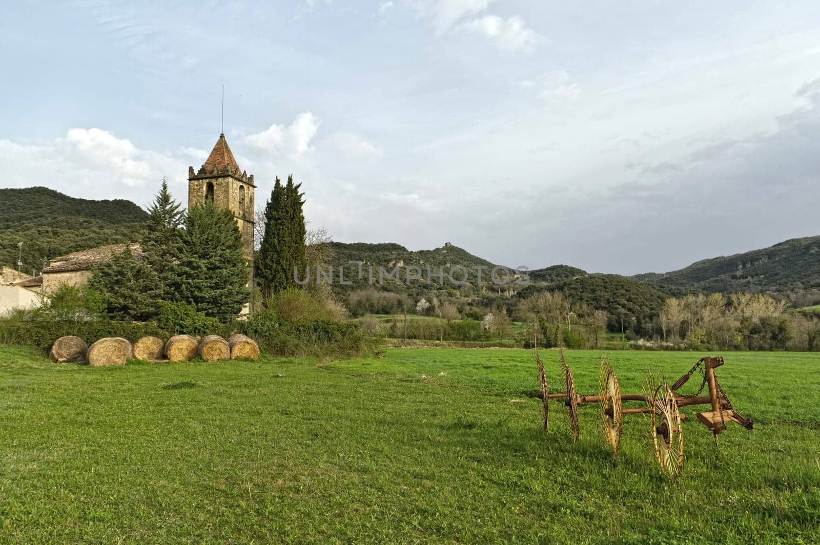 Typical Catalan countryside, rural grass with your mower, straw waltz and the church, surrounded by mountains.