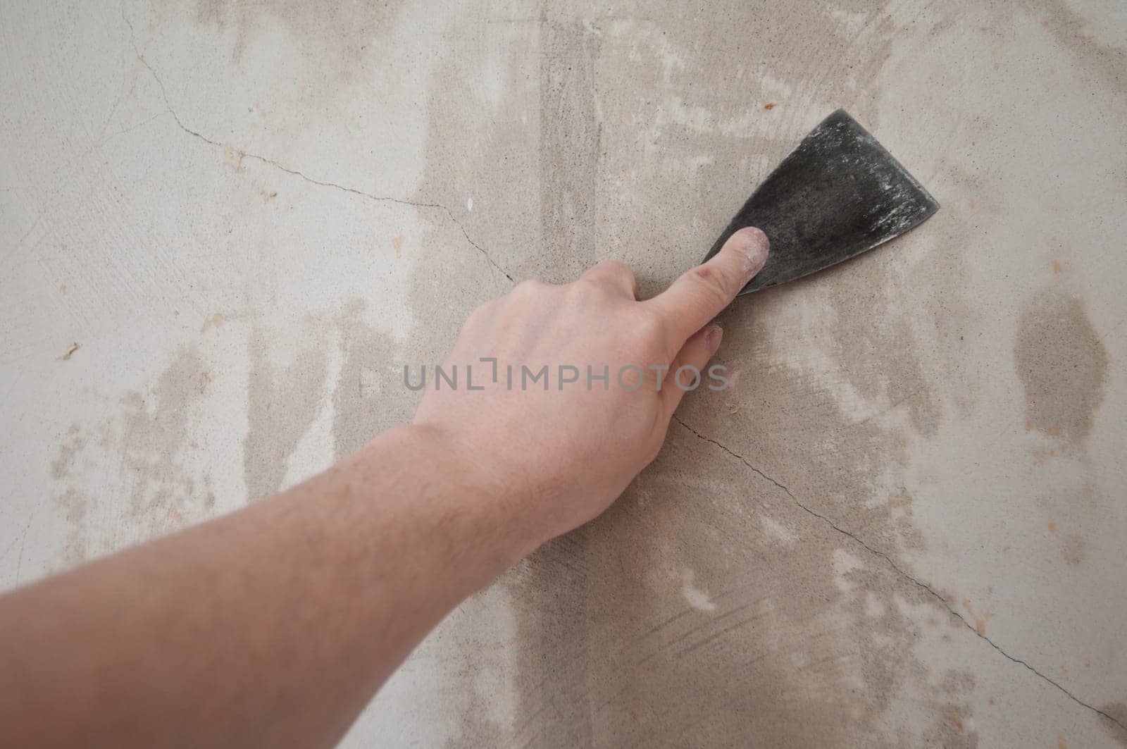 The cracks of a wall are filled with a spatula.
