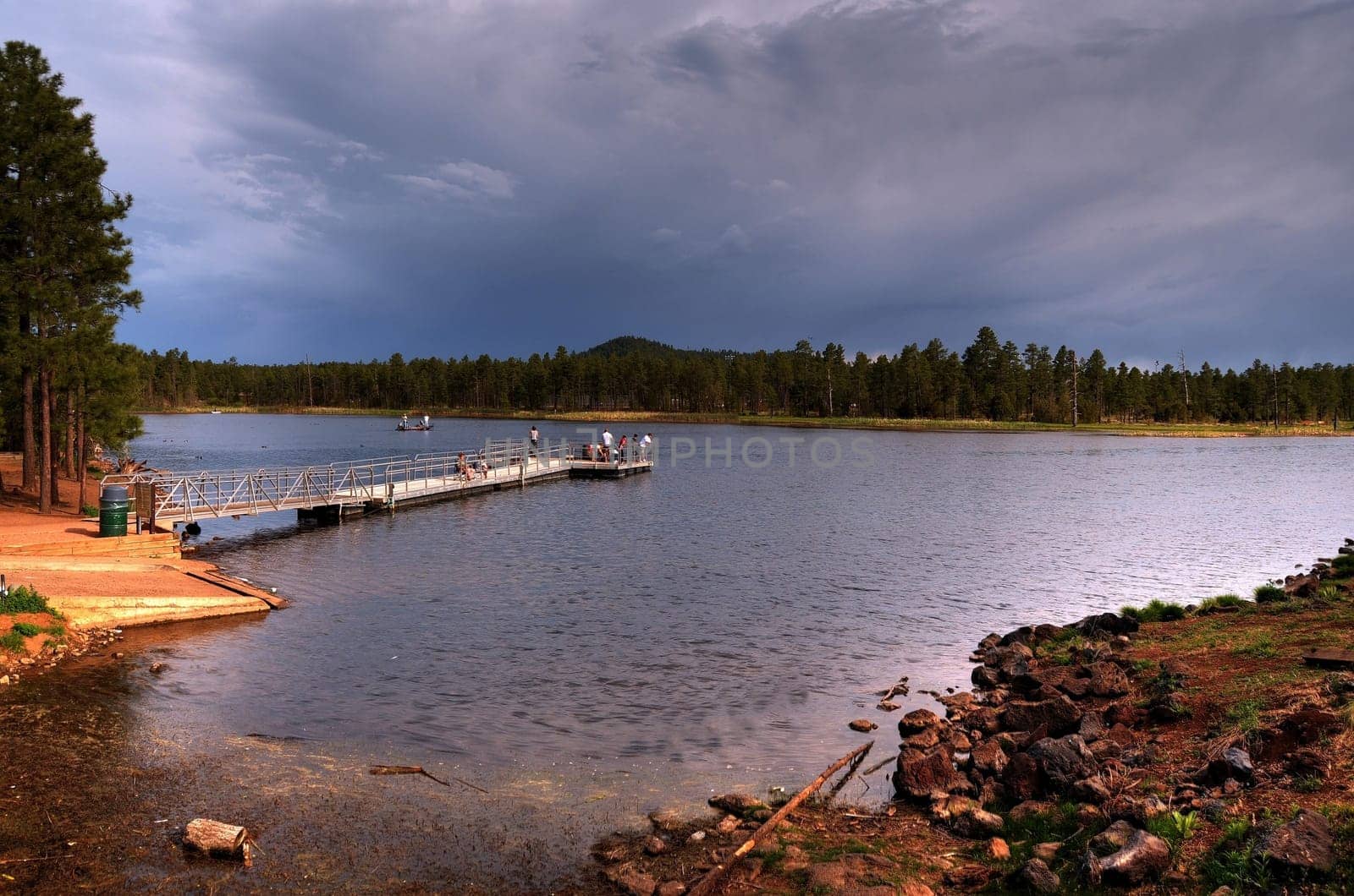A Mountain forest lake with people fishing