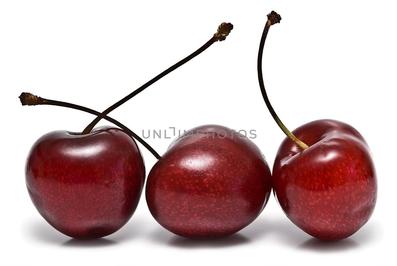 Fresh cherries on a white background and reflected on water.