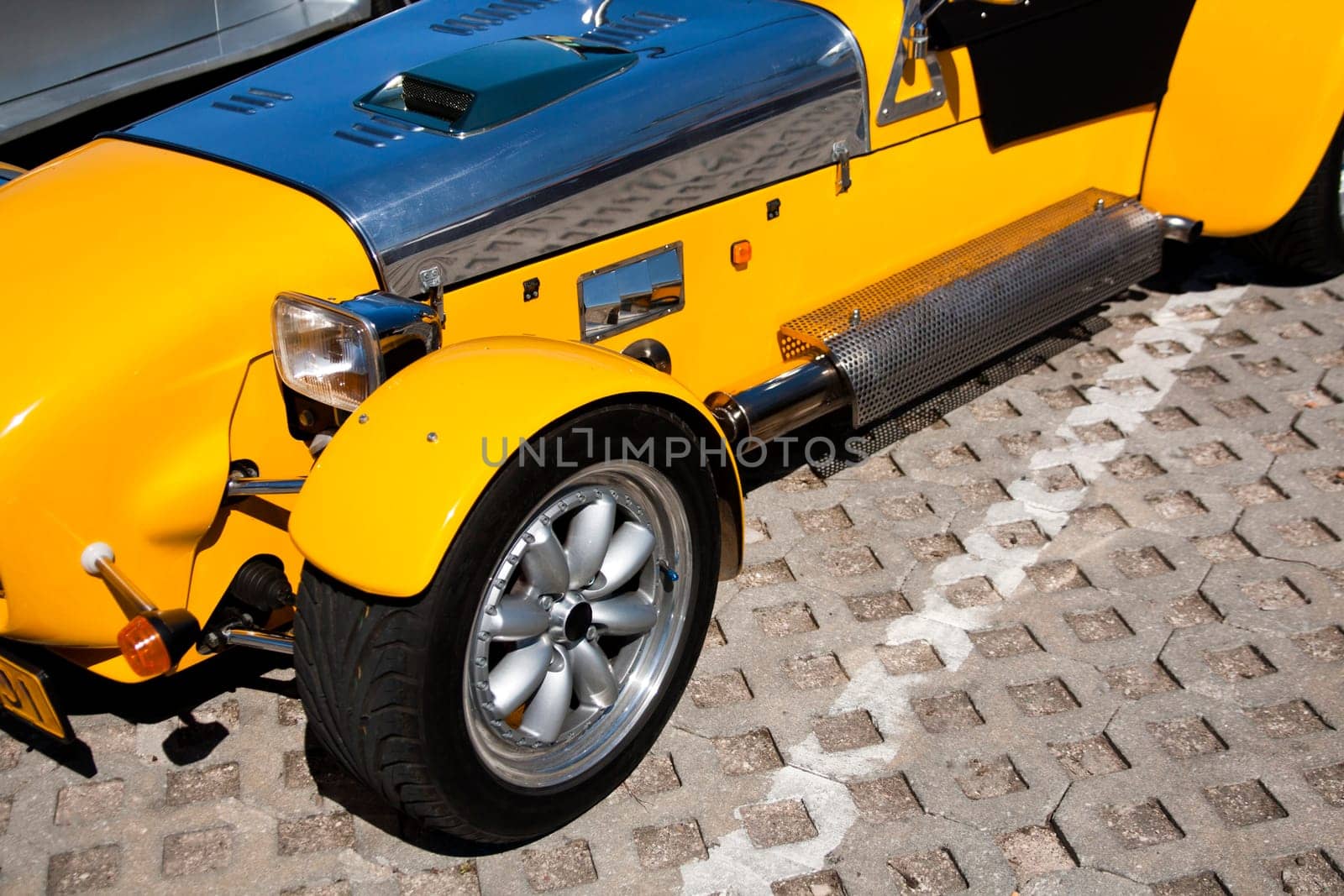 Close view of a weird yellow sports car parked on a park.