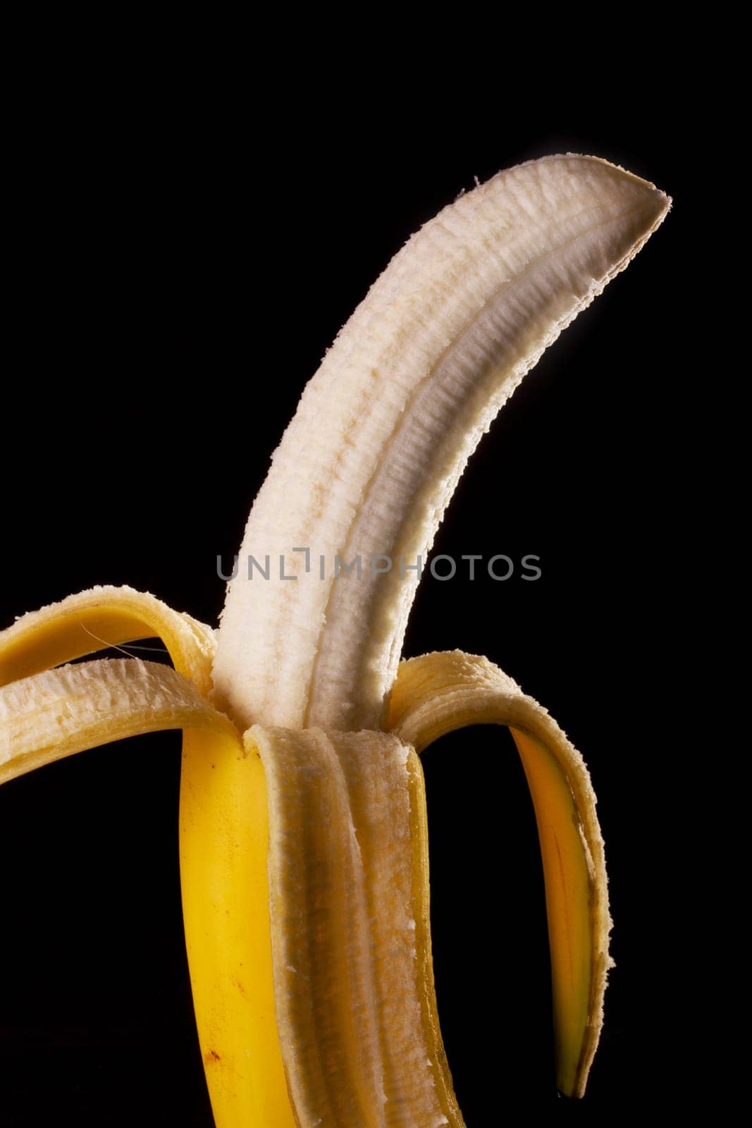 Close up view of peeled banana isolated on a black background.